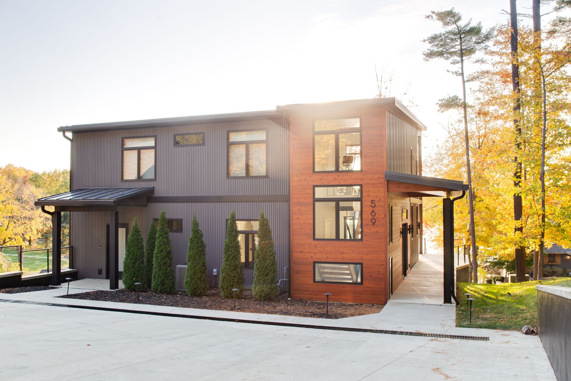 A large modern house with a lot of windows and trees surrounding it.