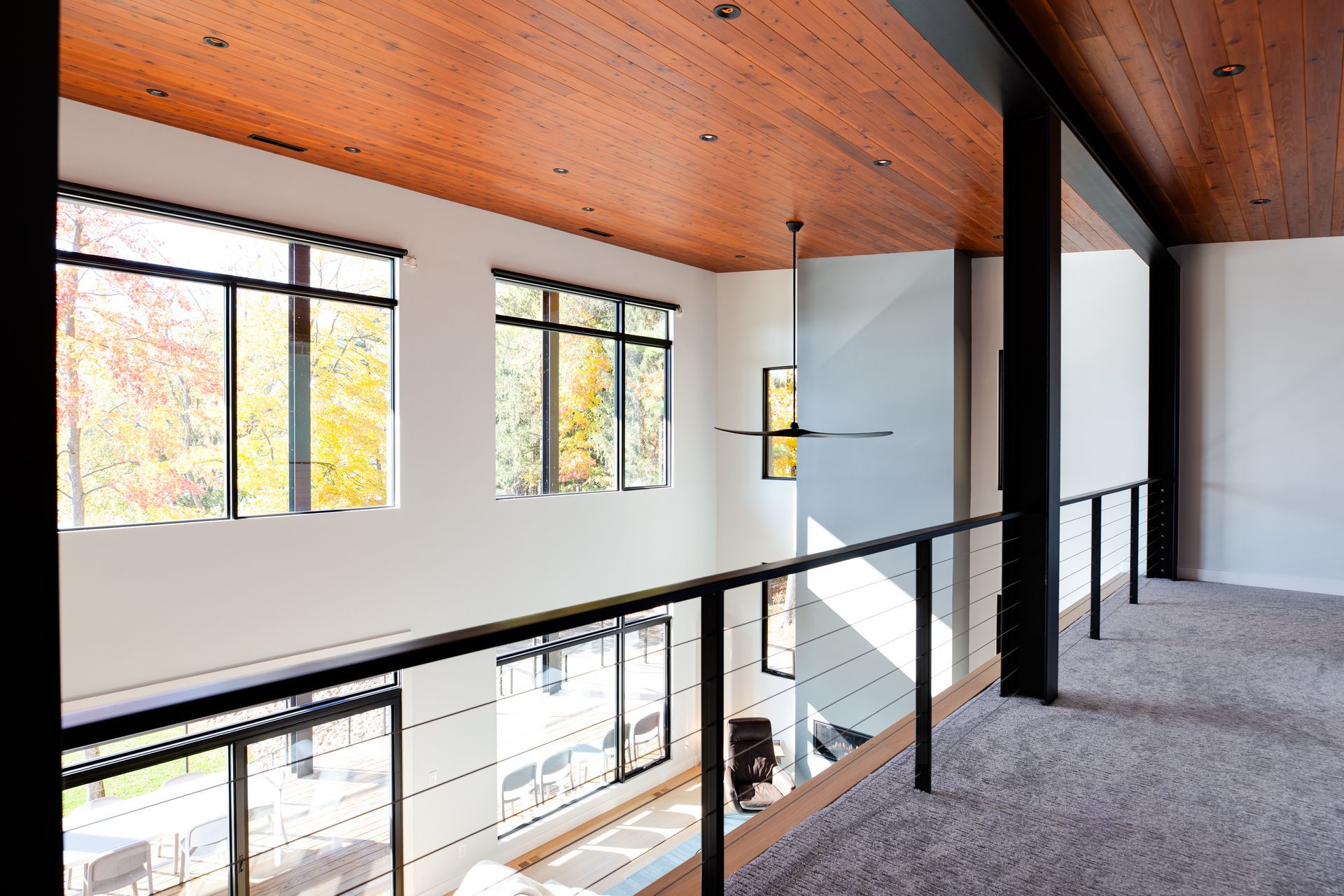 A hallway in a house with a wooden ceiling and lots of windows.