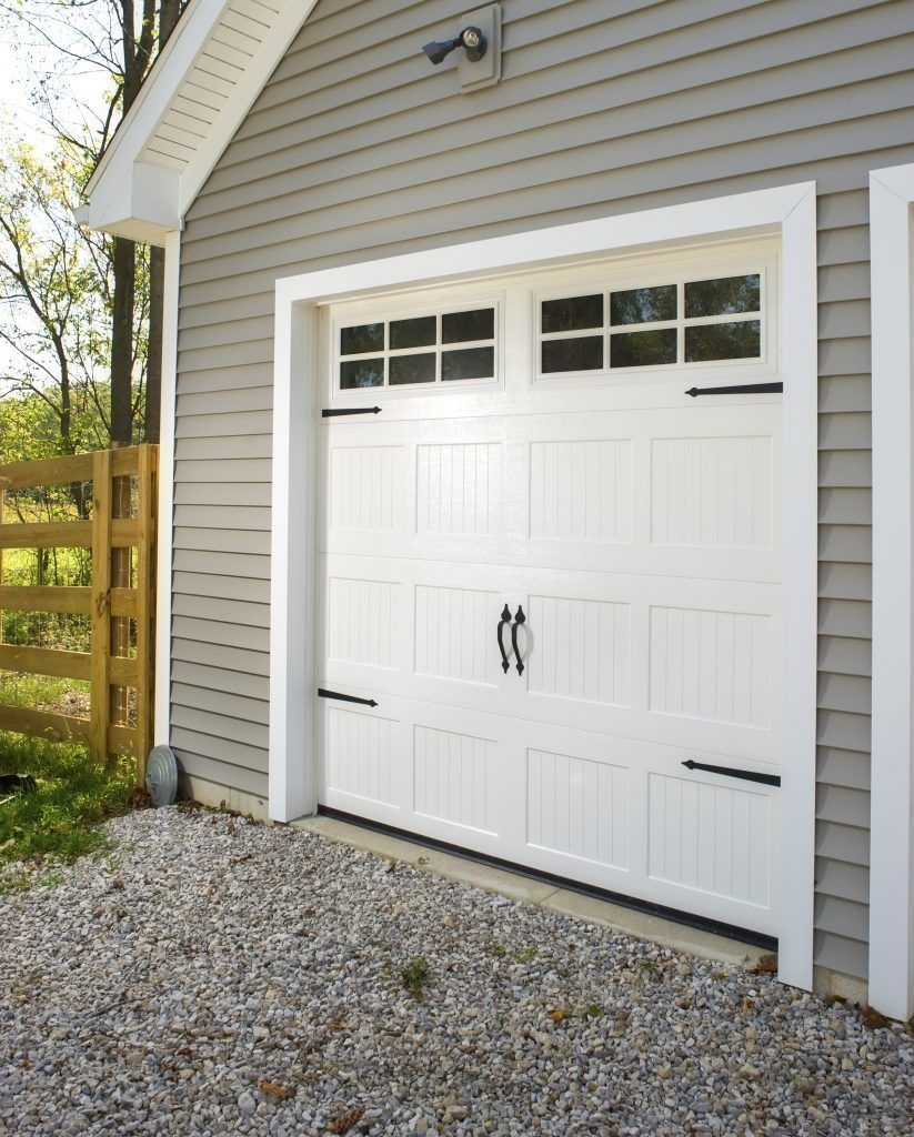 A white garage door with a wooden fence in the background.