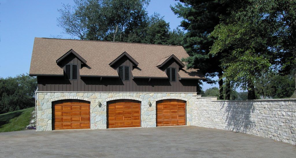 A large stone garage with three wooden garage doors.