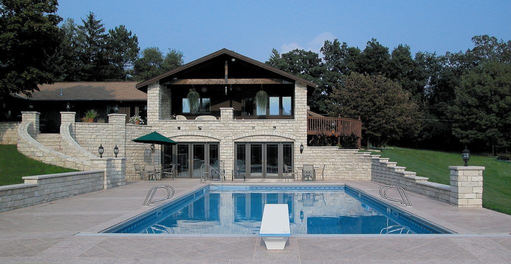 A large house with a large swimming pool in front of it.