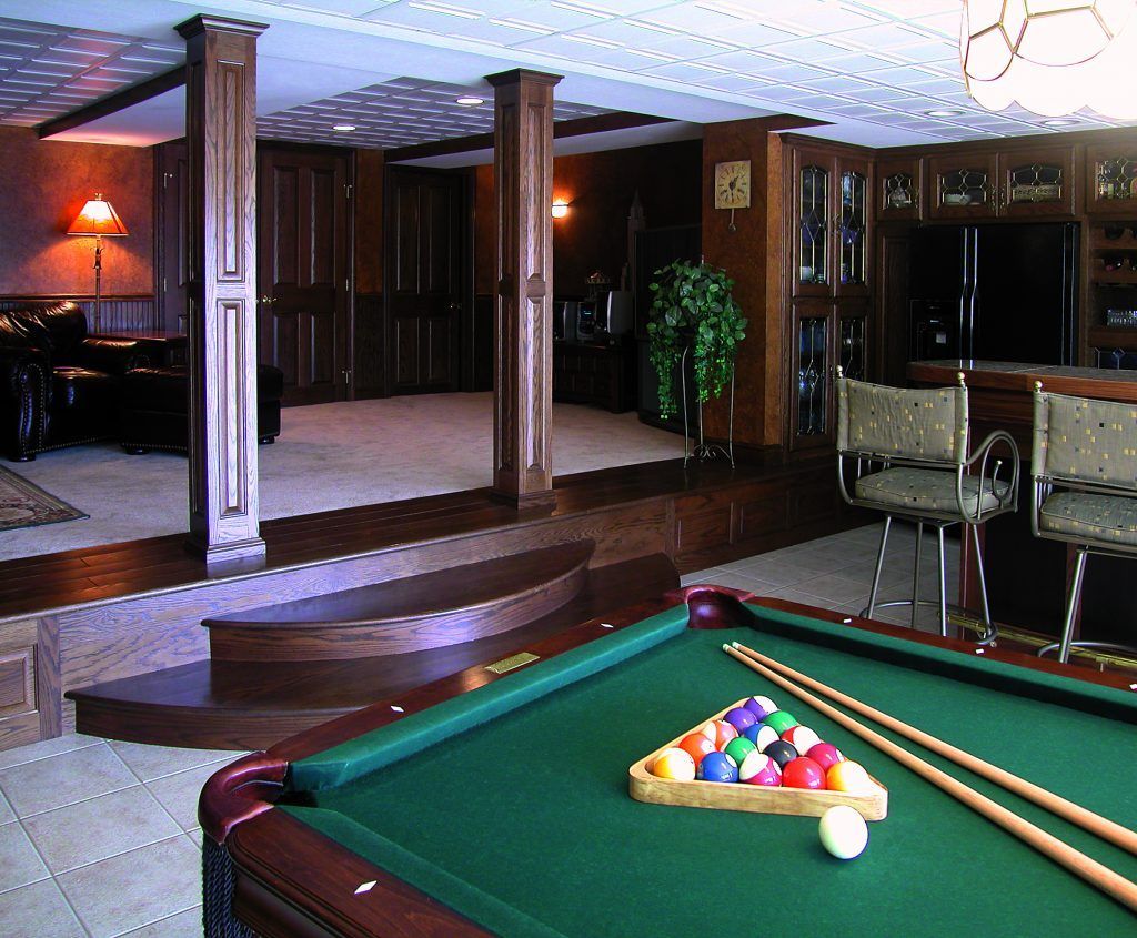 A pool table with balls and cues in a living room.