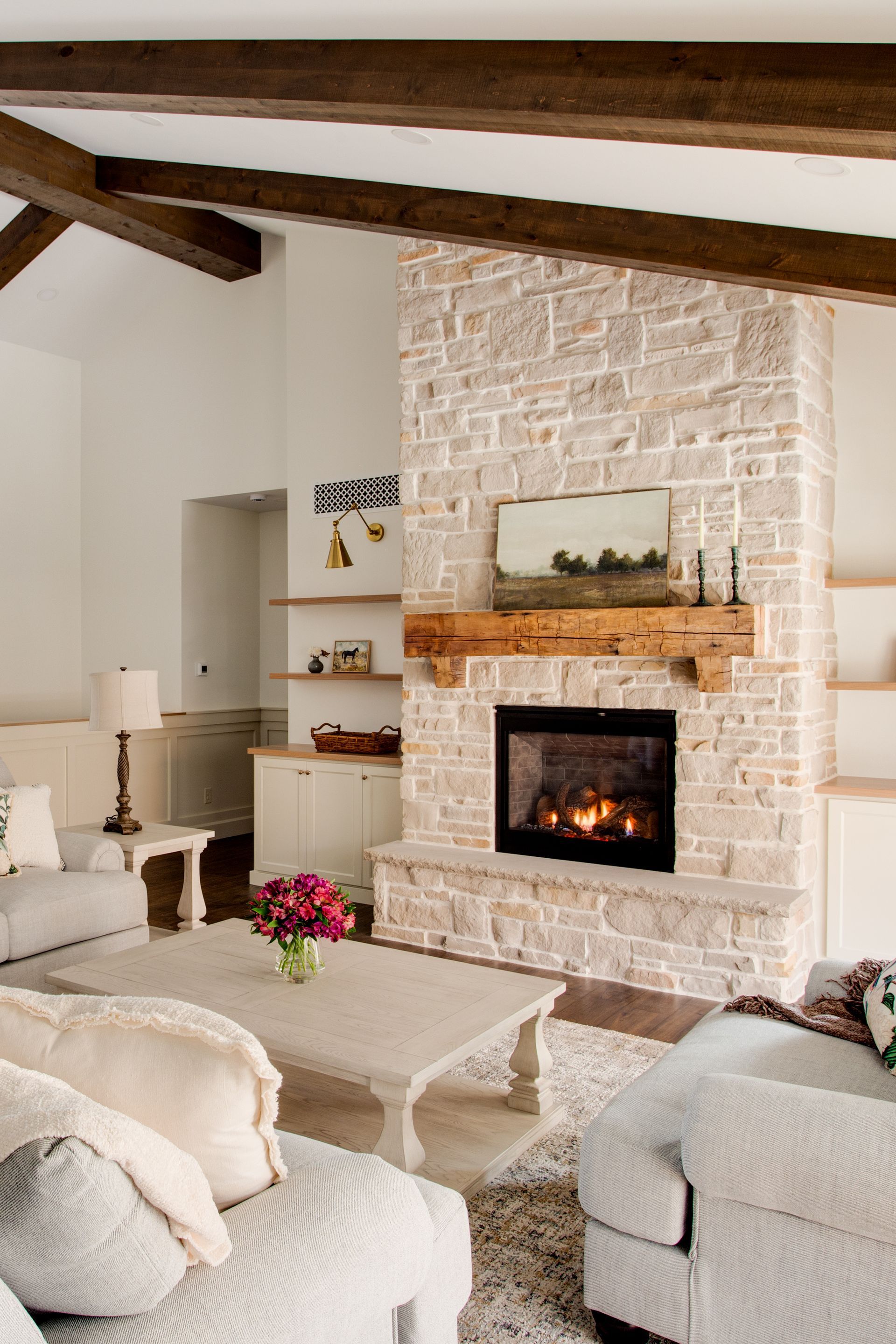 A living room with a stone fireplace and wooden beams.
