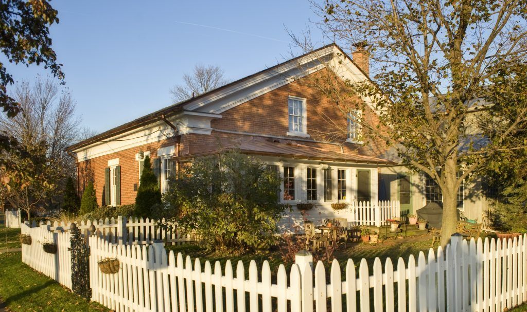 A brick house with a white picket fence around it.