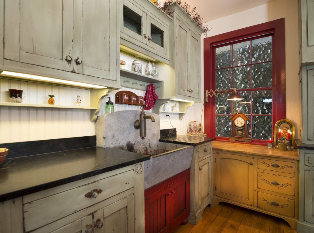 A kitchen with a sink and a window with a clock on it.