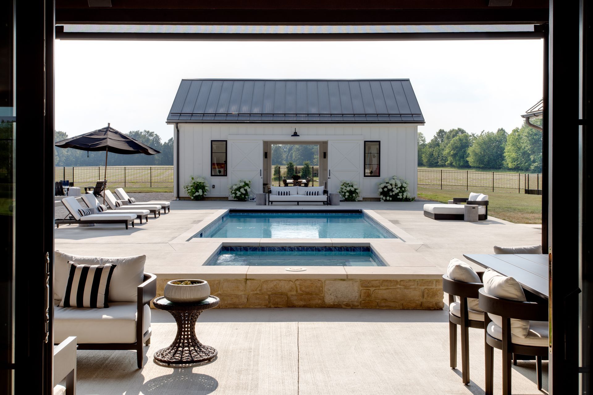 A house with a large swimming pool in front of it with sun chairs.
