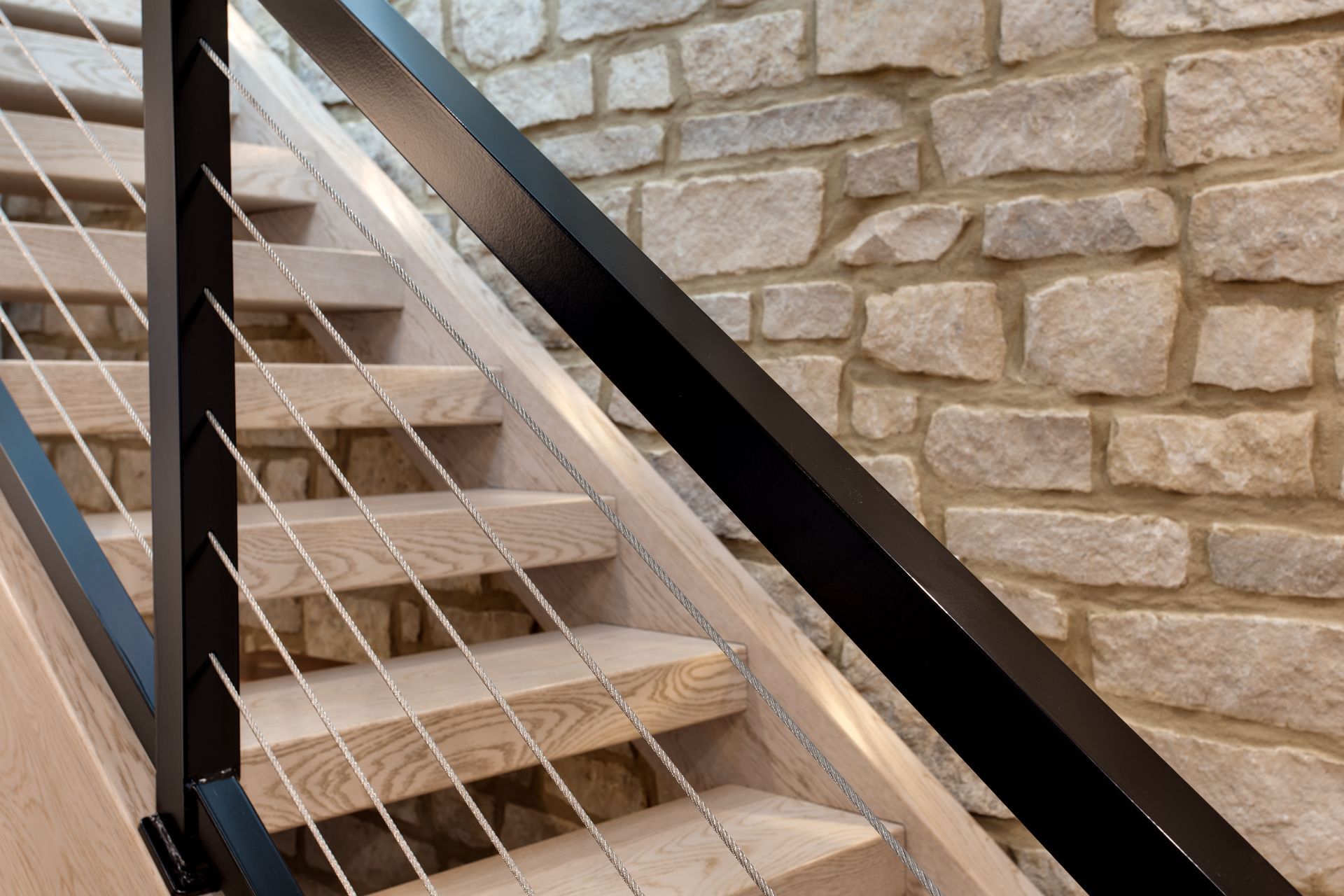 A staircase with a black railing and a brick wall in the background.