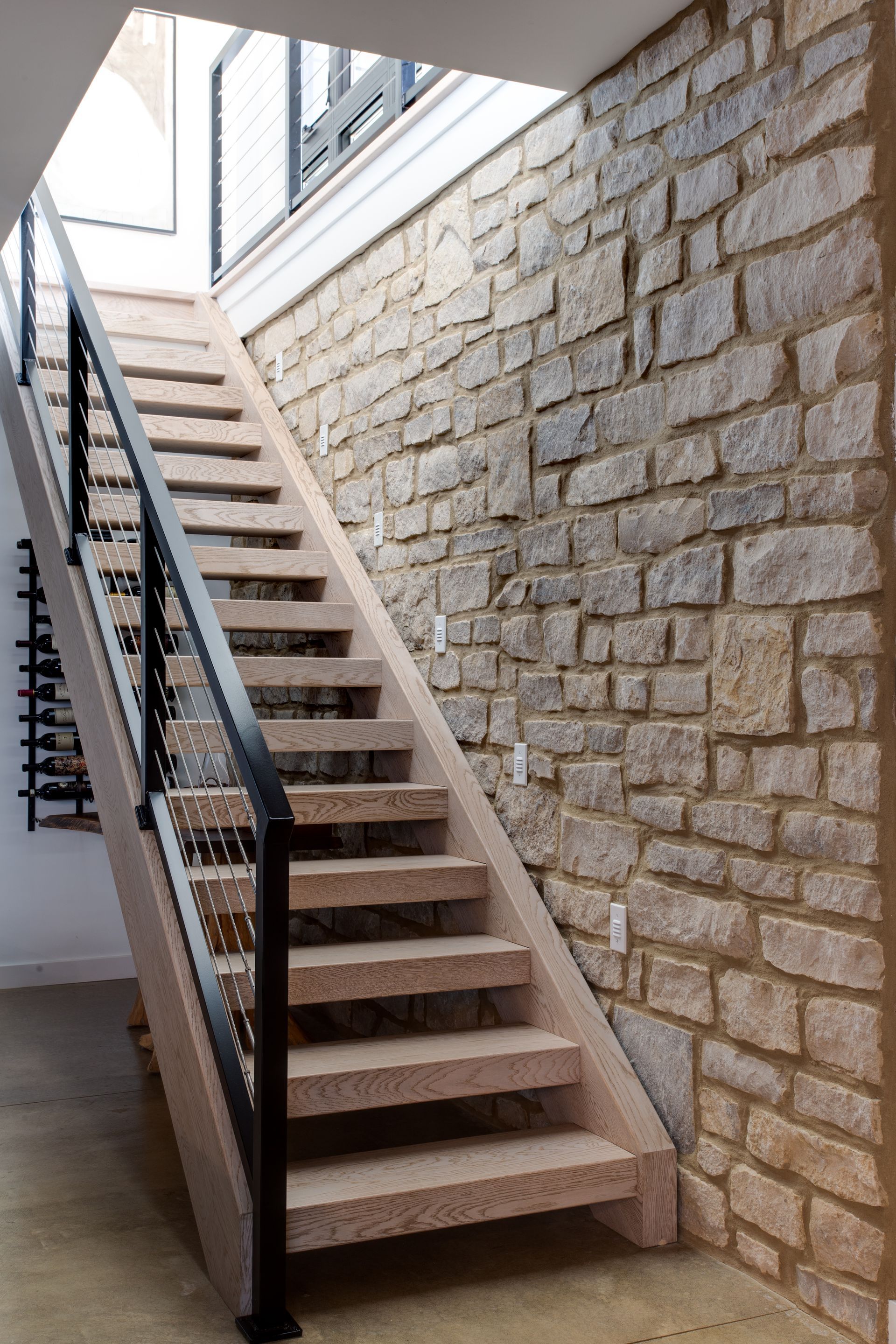 A staircase leading up to a stone wall with a black railing.