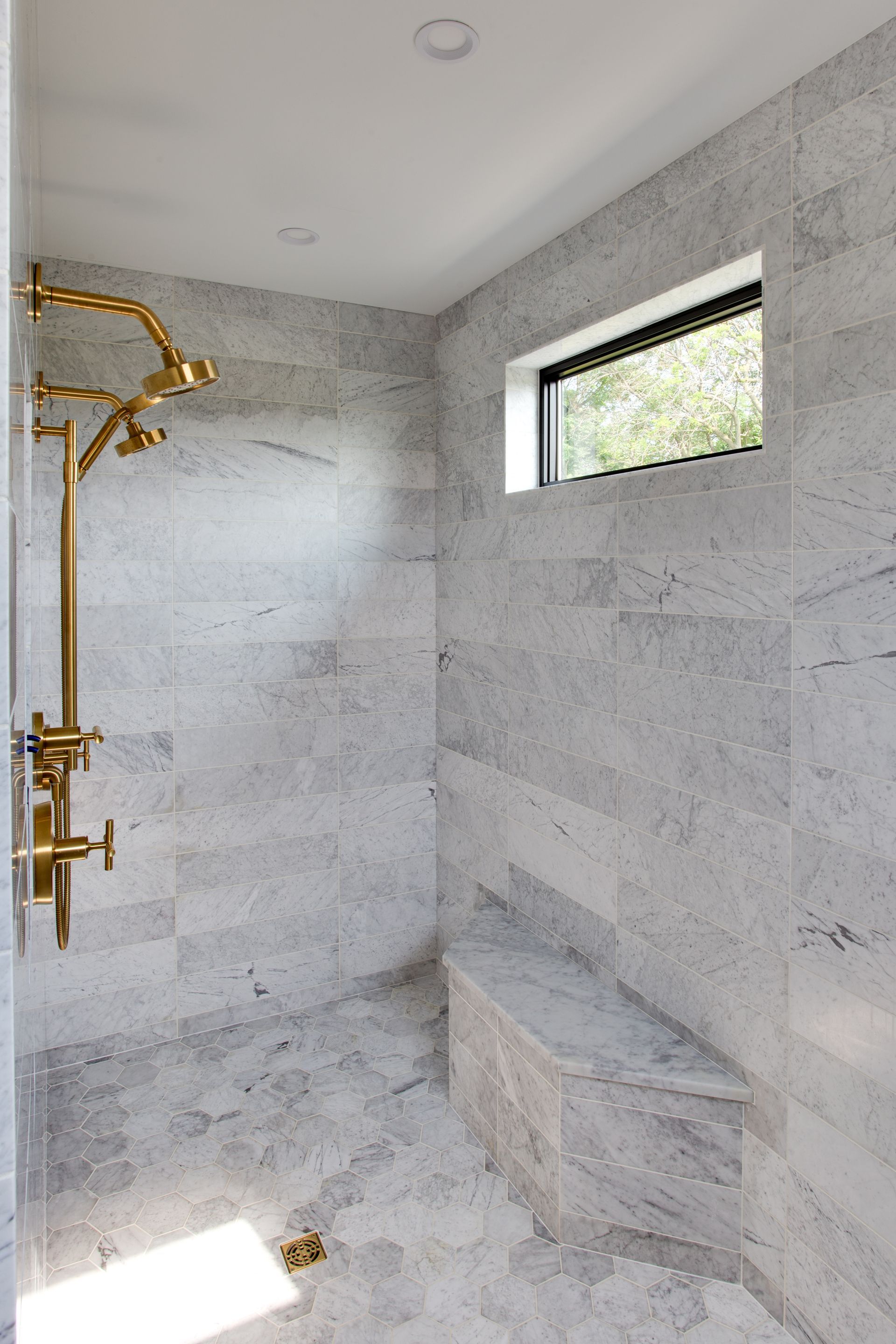 A bathroom with a walk in shower and a window.
