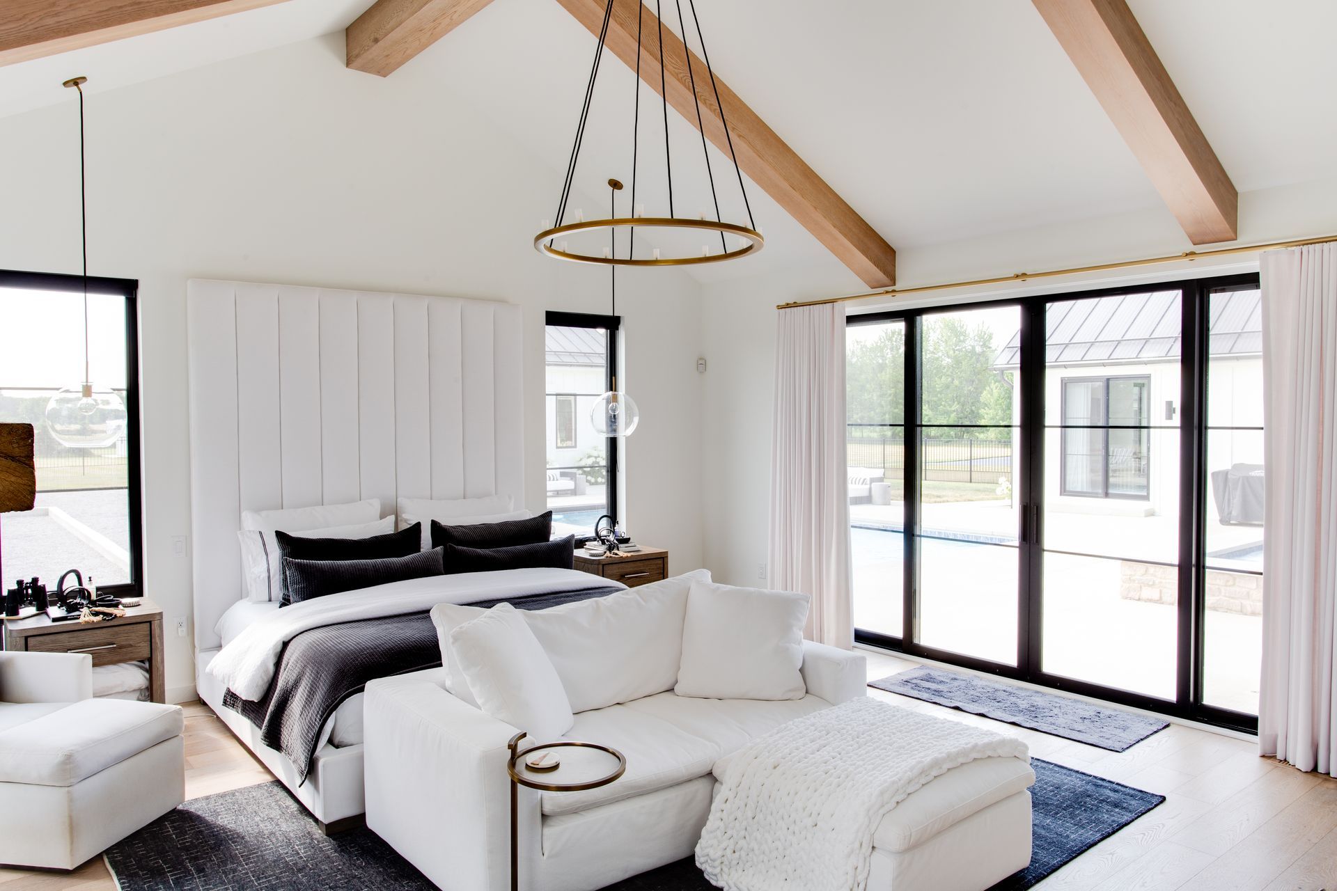 A bedroom with a bed, couch, and lots of windows.