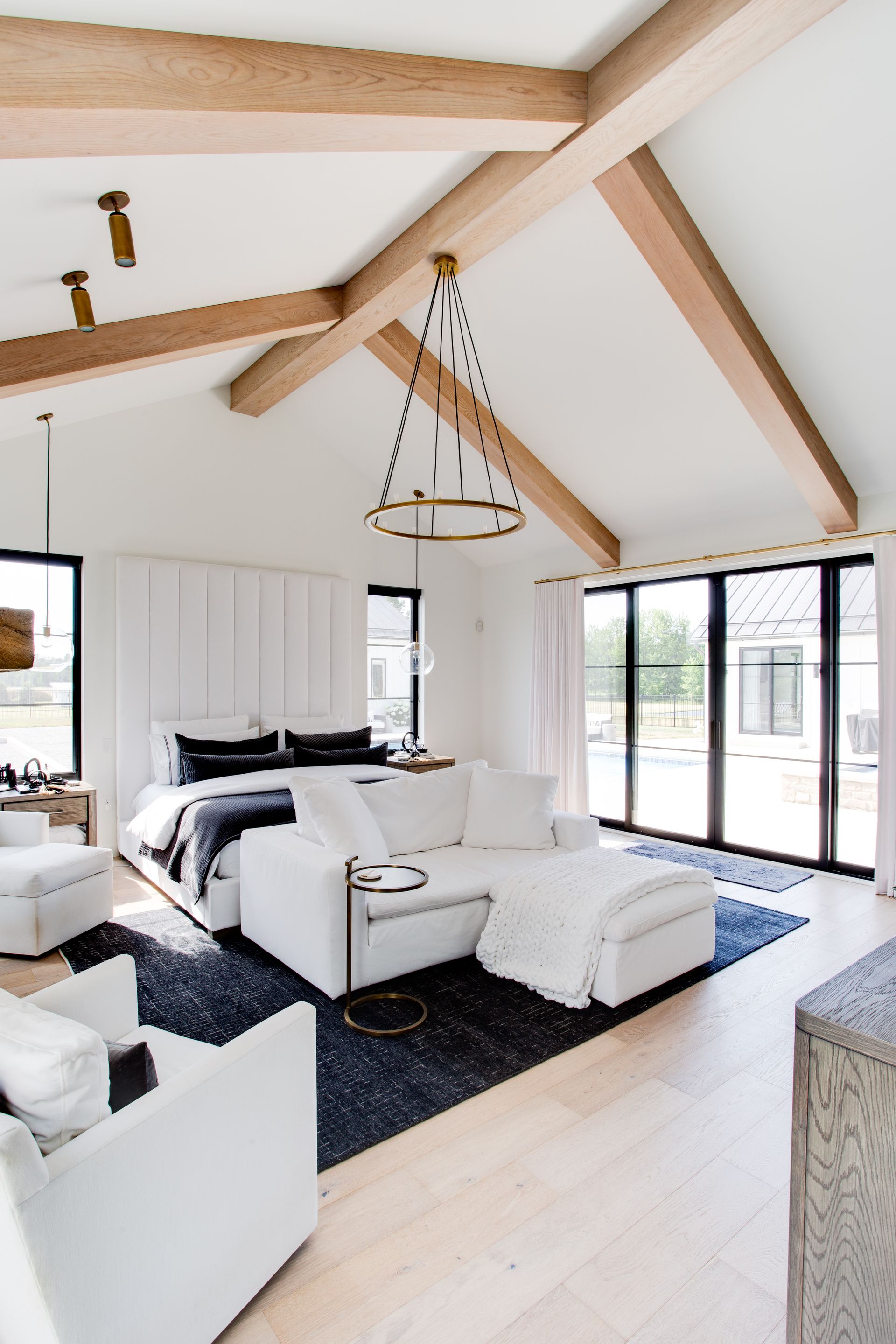 A bedroom with a bed, couch, chairs and a chandelier.
