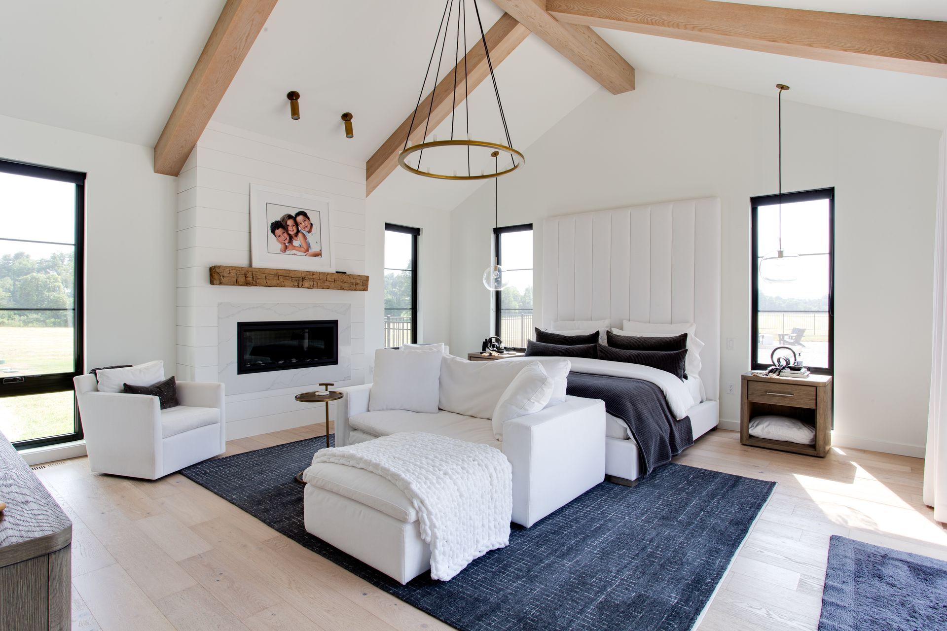 A bedroom with a bed, couch, chair and fireplace.