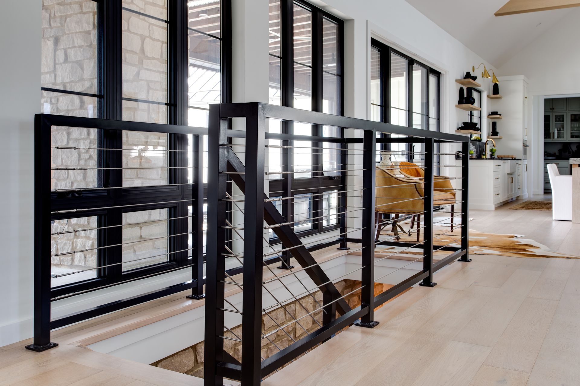 A staircase in a house with a black railing and lots of windows.