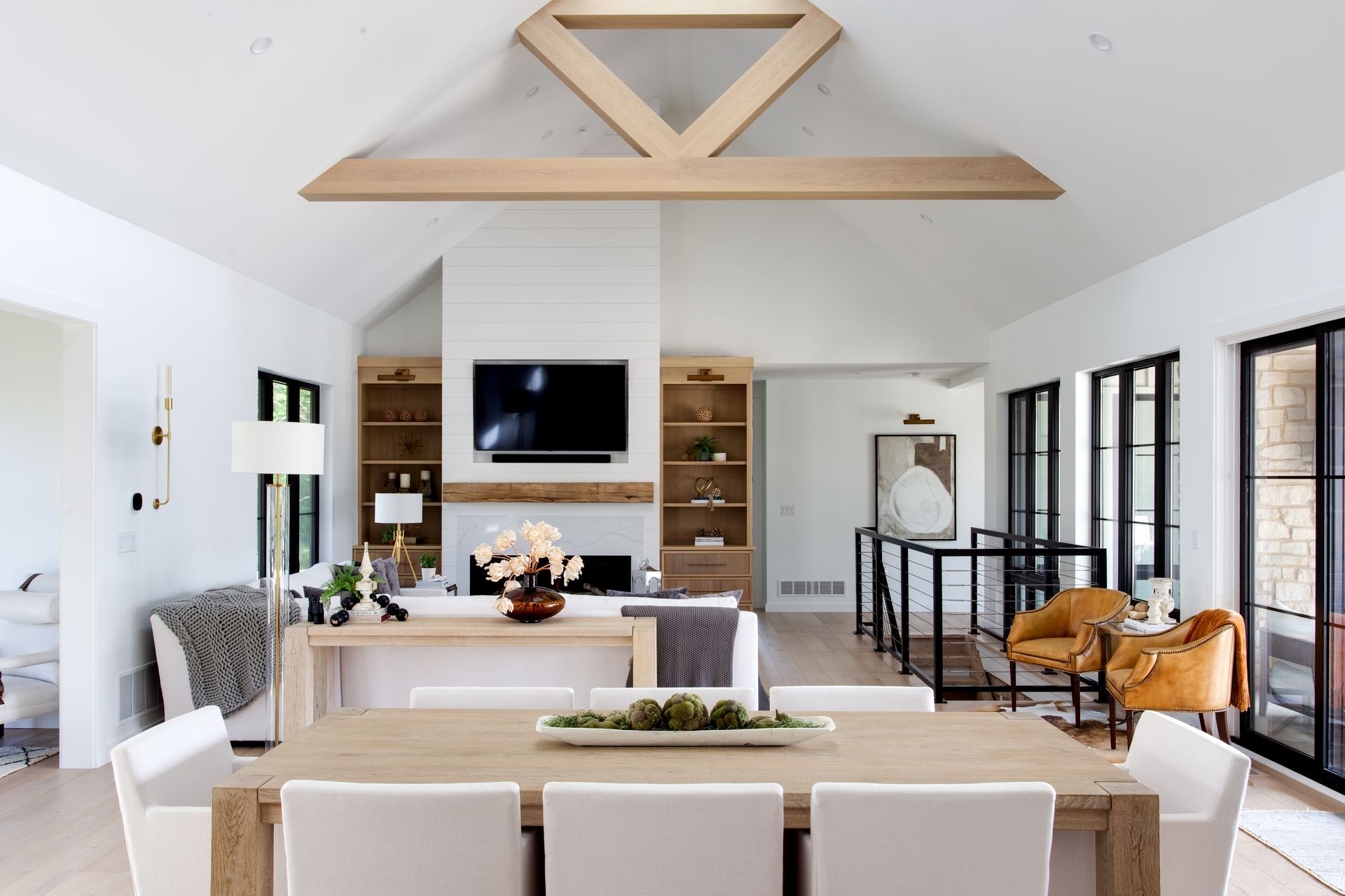 A living room with a table and chairs and a television on the wall.