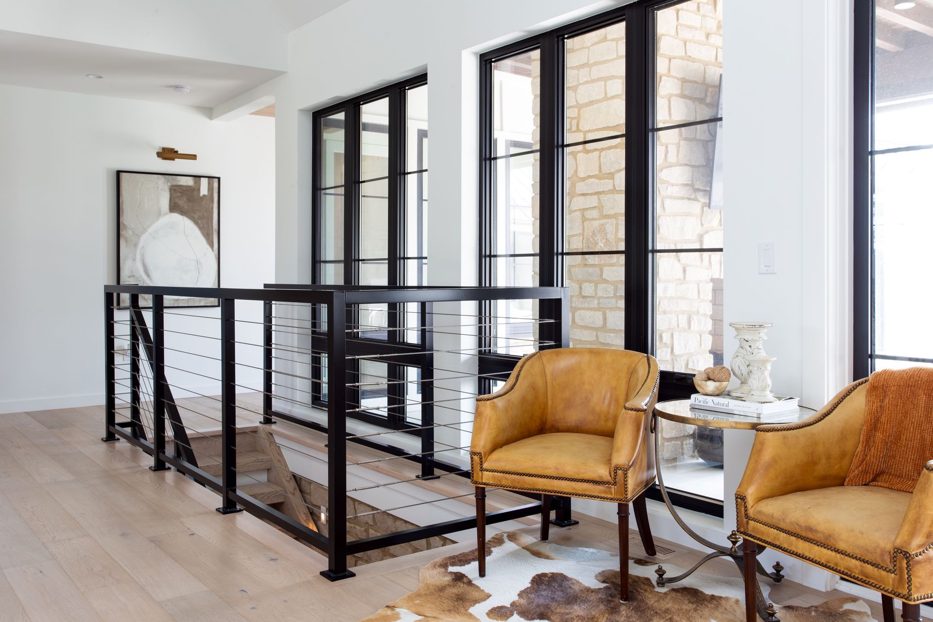 A modern home living room with two chairs, a table, and a railing.