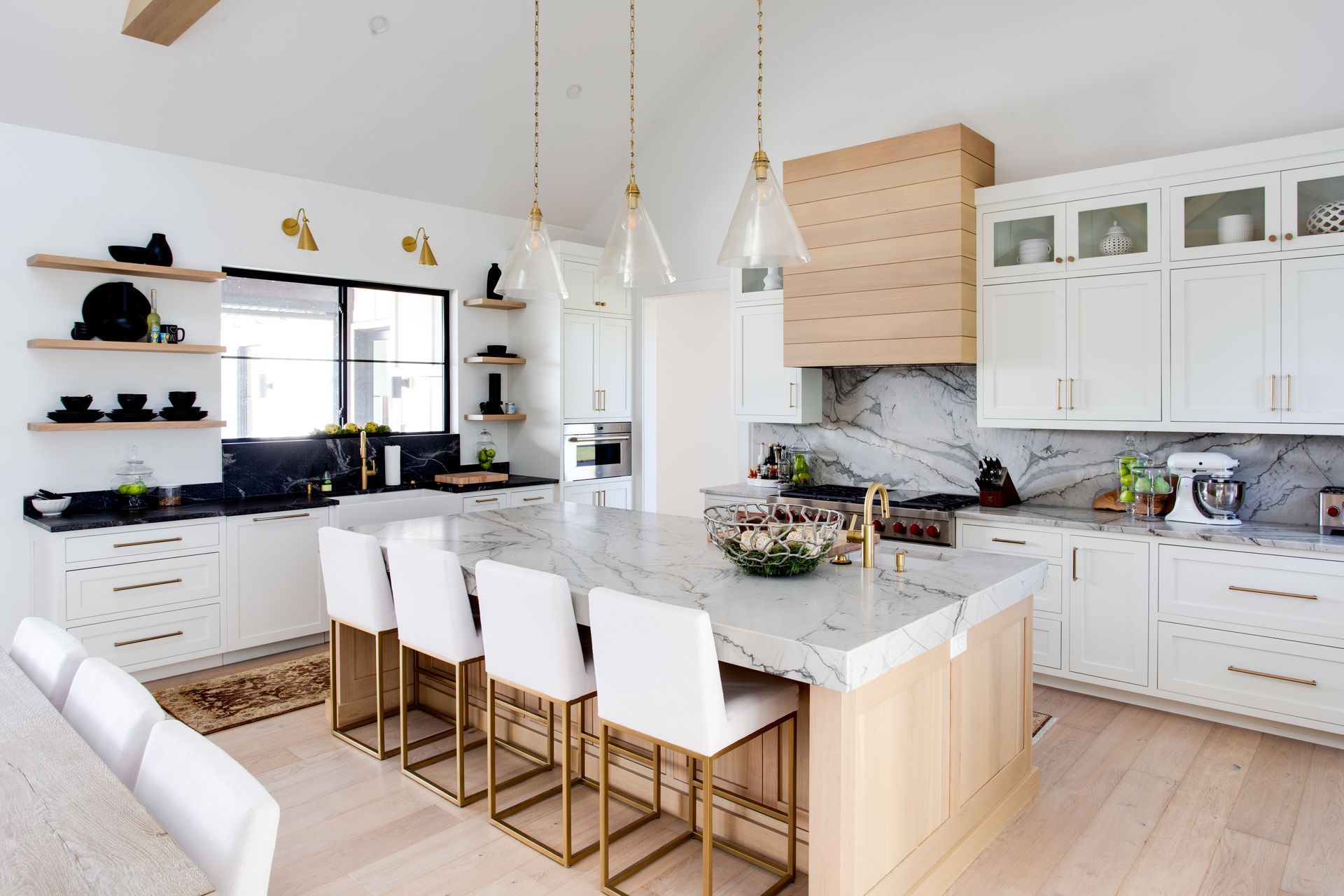 A kitchen with white cabinets , marble counter tops , and a large island.