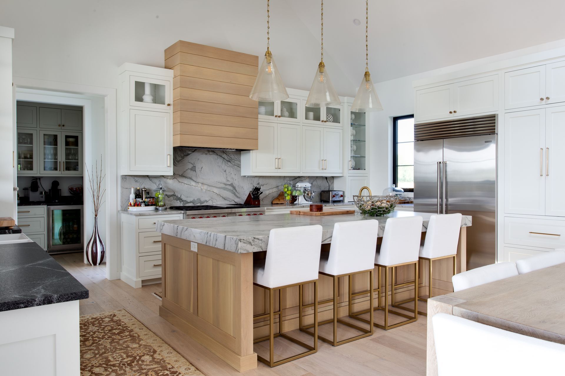 A kitchen with white cabinets, marble counter tops, and stainless steel appliances.