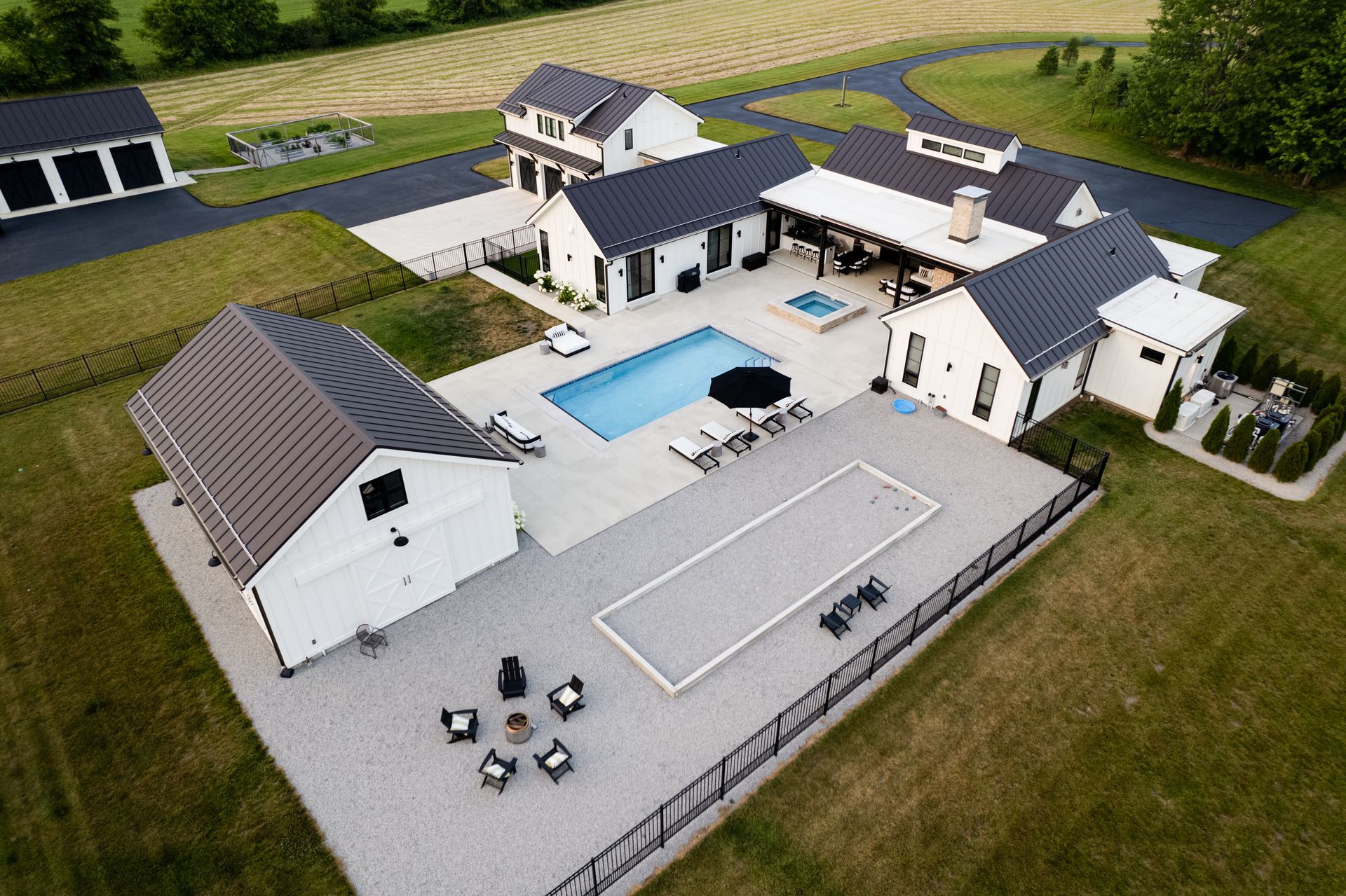 An aerial view of a large house with a swimming pool and a fire pit.