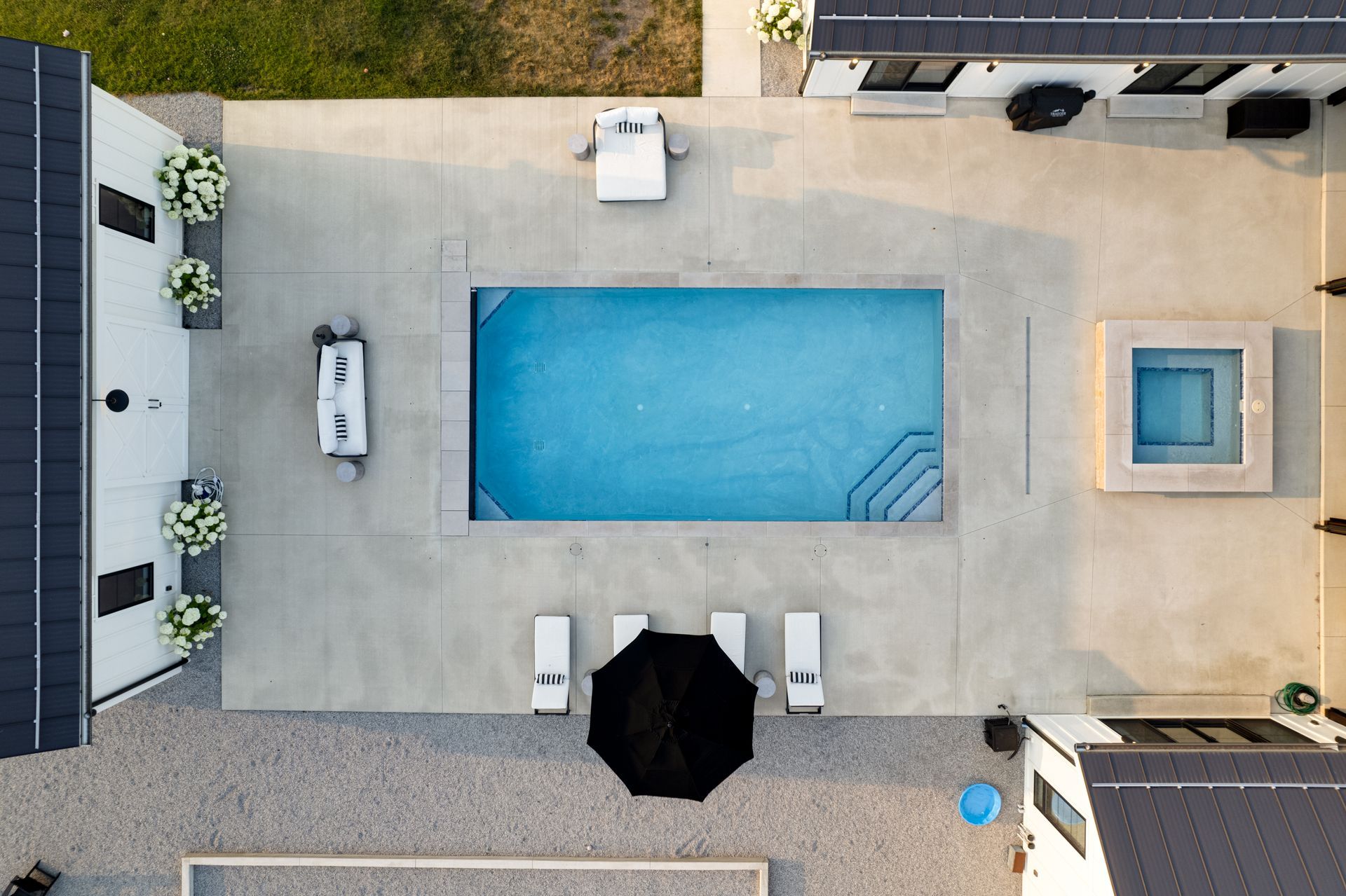 An aerial view of a large swimming pool in the backyard of a house.
