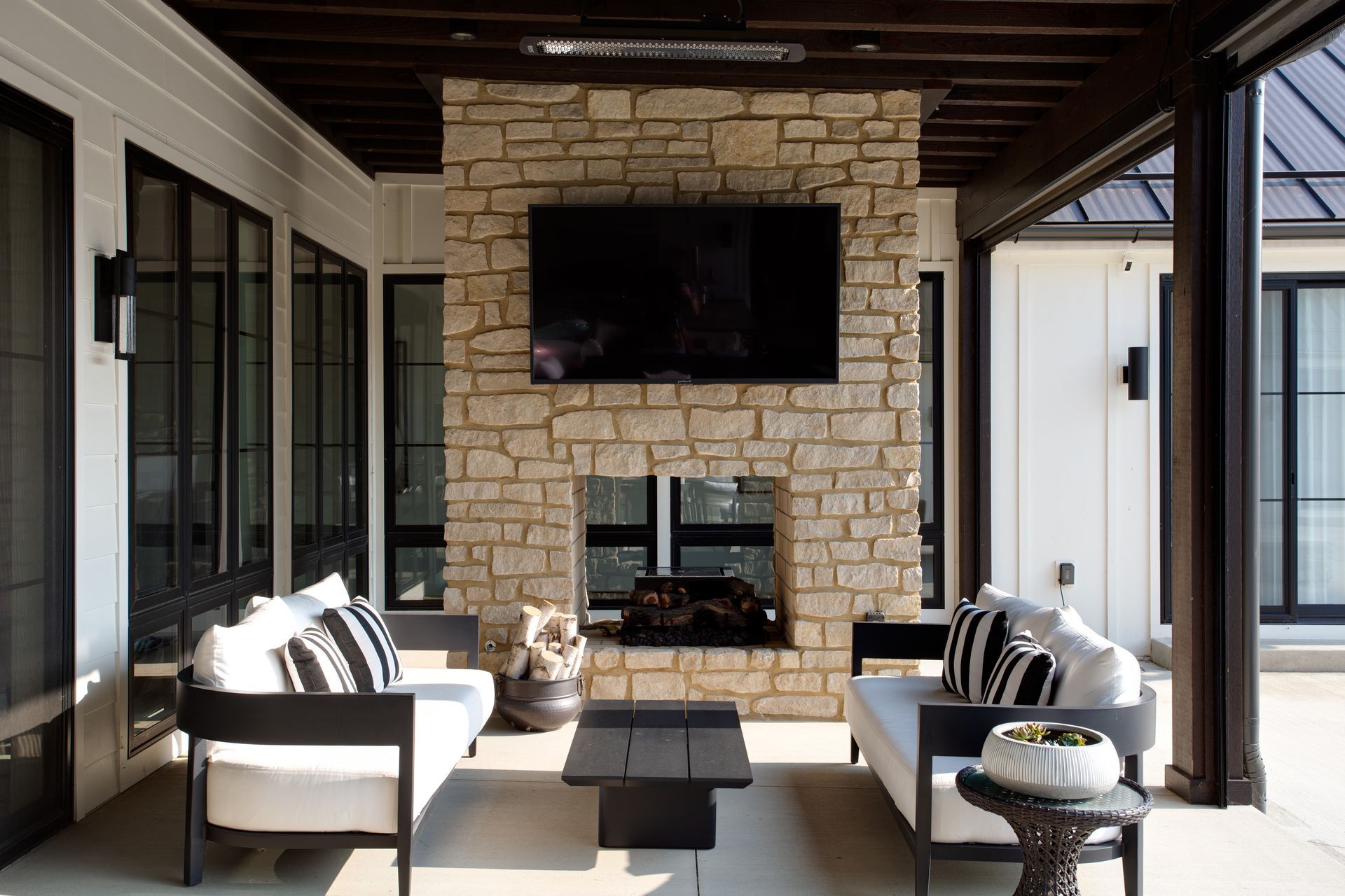 An pool house room with couches, a fireplace, and a flat screen tv on the wall.