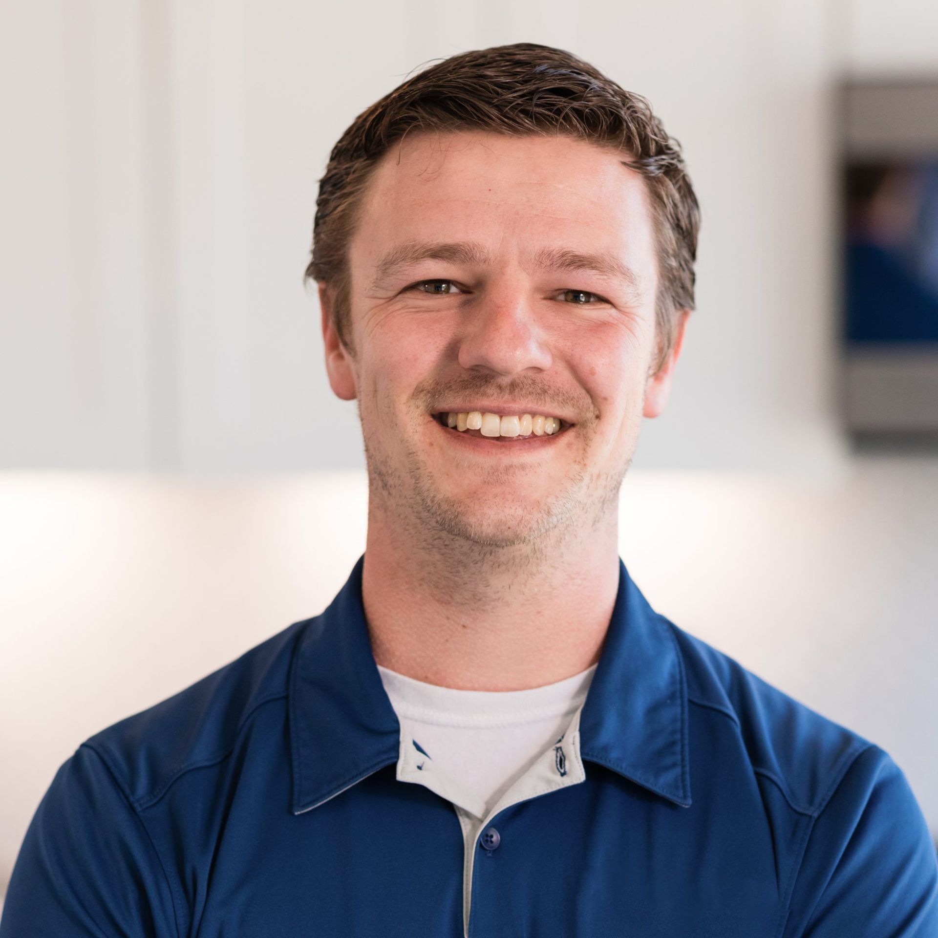 A man in a blue shirt is smiling for the camera.