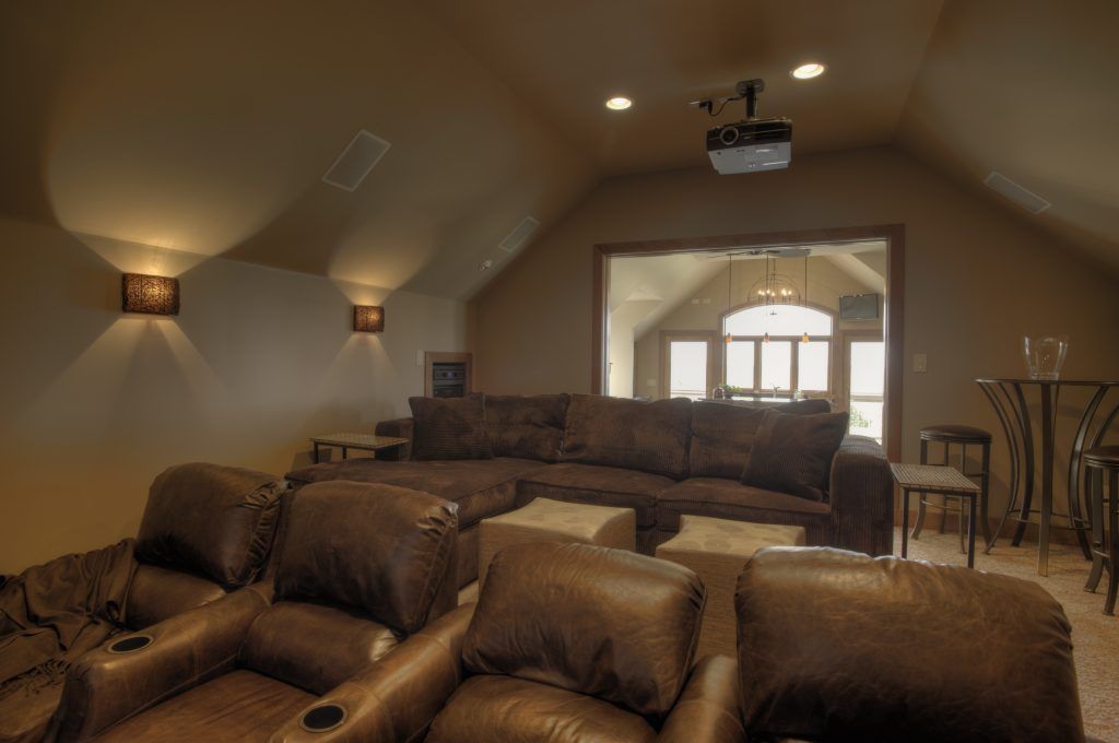 A home theater with brown leather chairs and a projector.