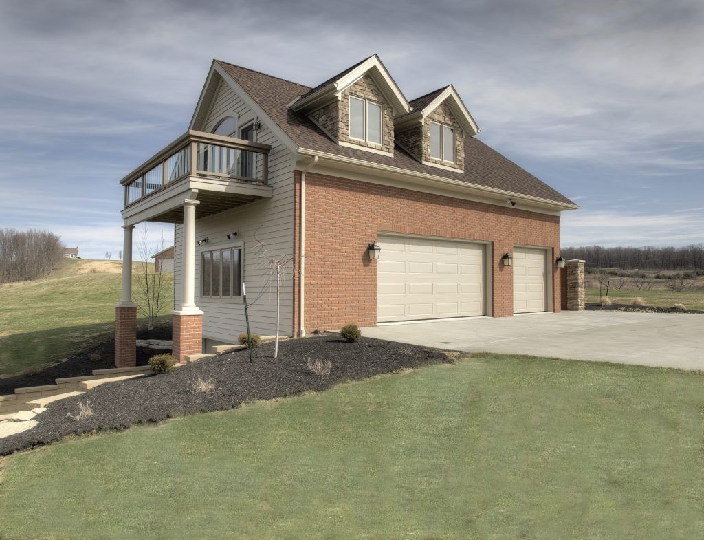 A brick house with two garage doors and a balcony.