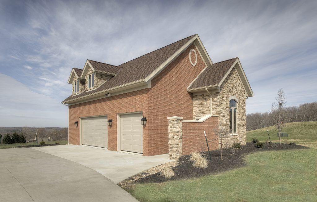 A large brick and stone garage with three garage doors.