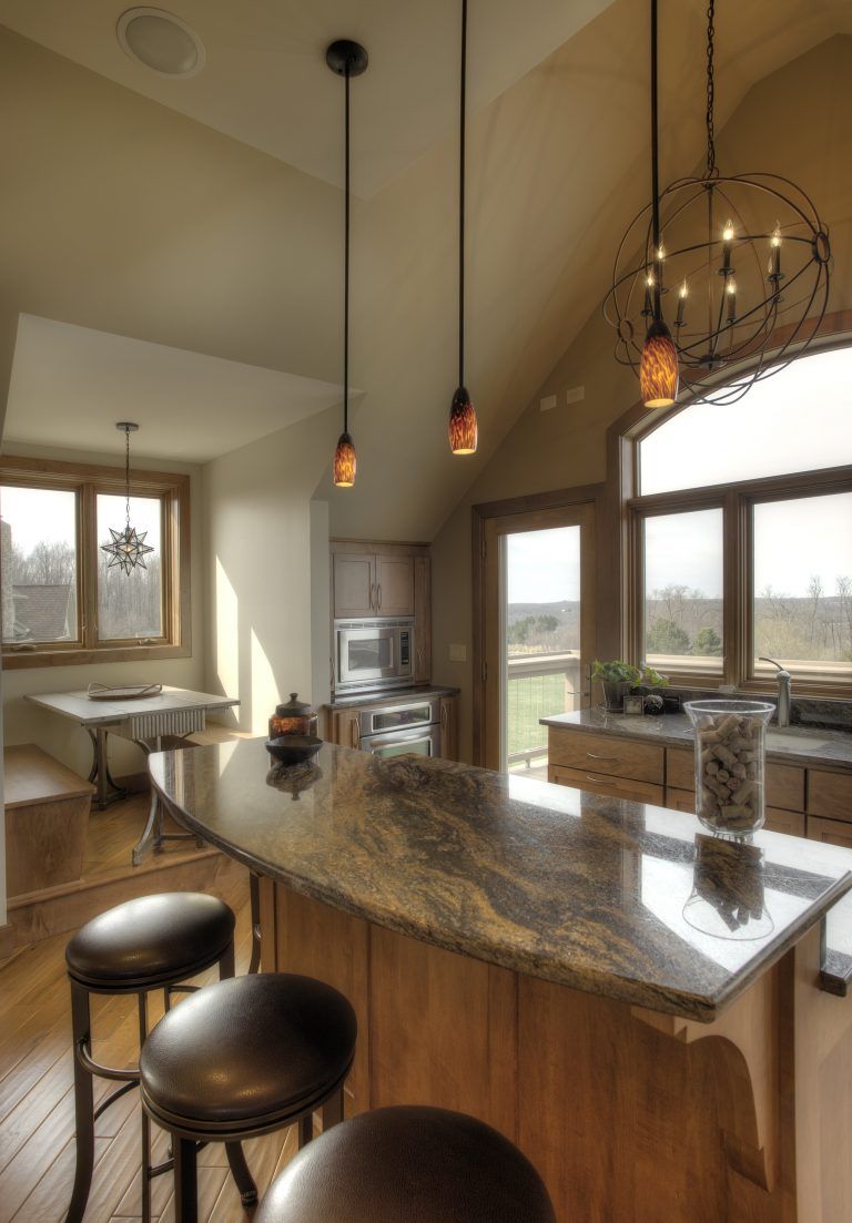 A kitchen with a large granite counter top and stools.