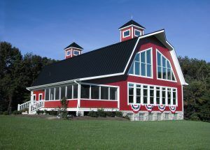 A large red barn with a black roof and lots of windows.