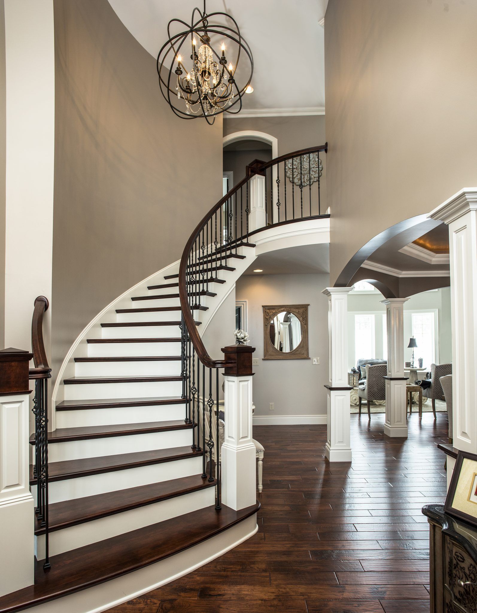 A curved staircase in a house with a chandelier hanging from the ceiling