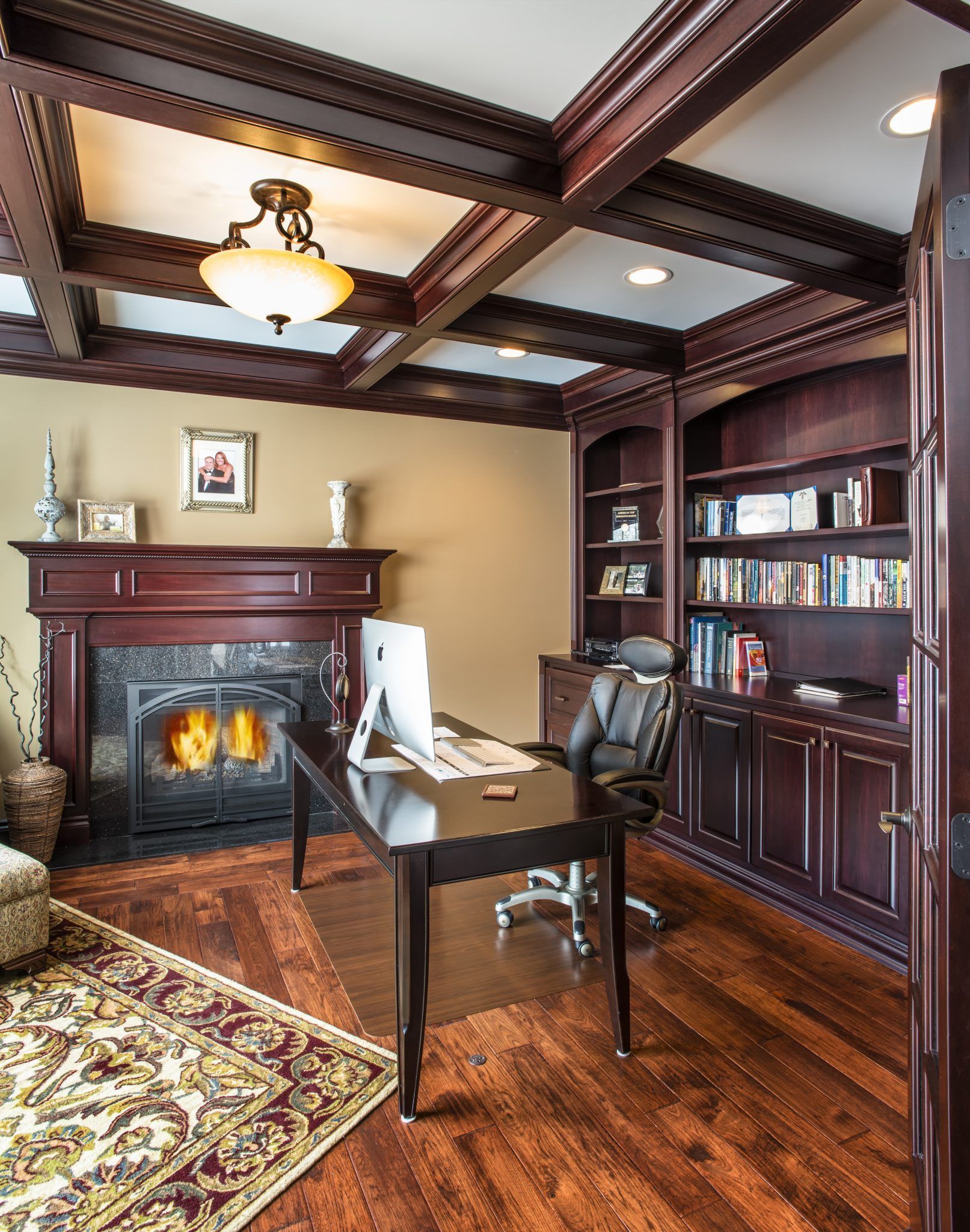 A home office with a desk , chair , computer and fireplace.