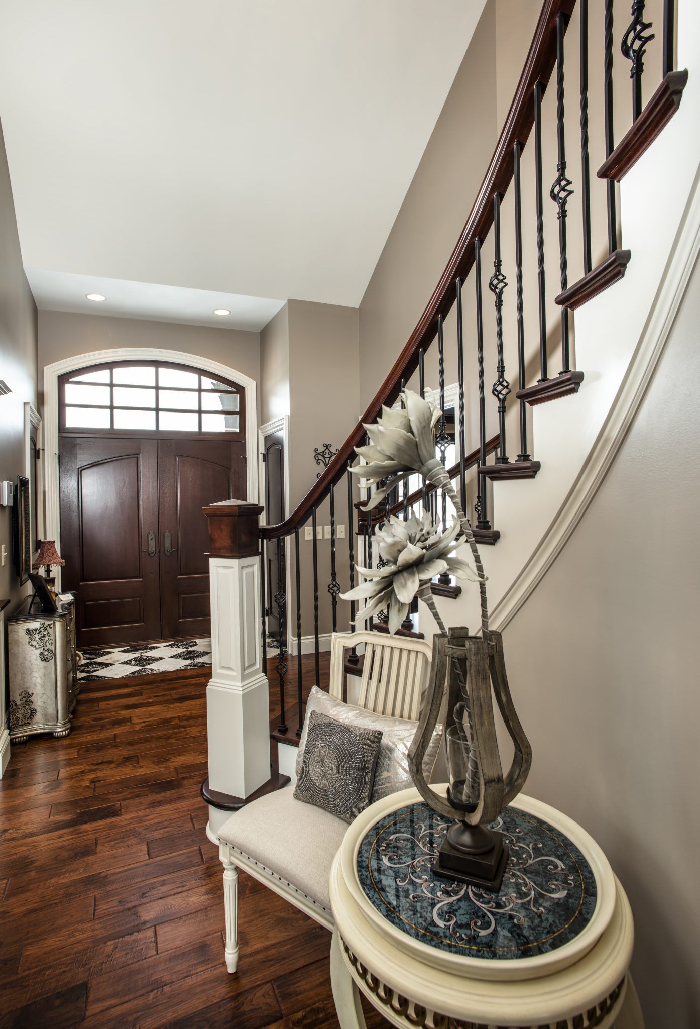 A hallway with a staircase and a table with a vase of flowers on it.