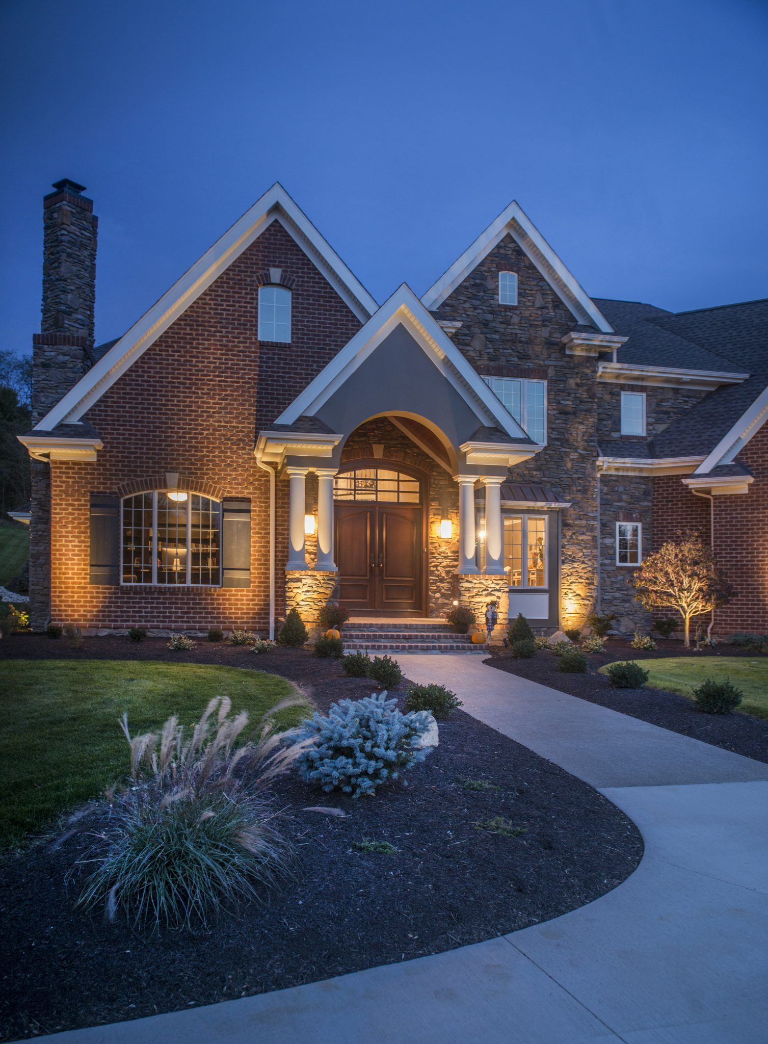 A large brick and stone house is lit up at night.