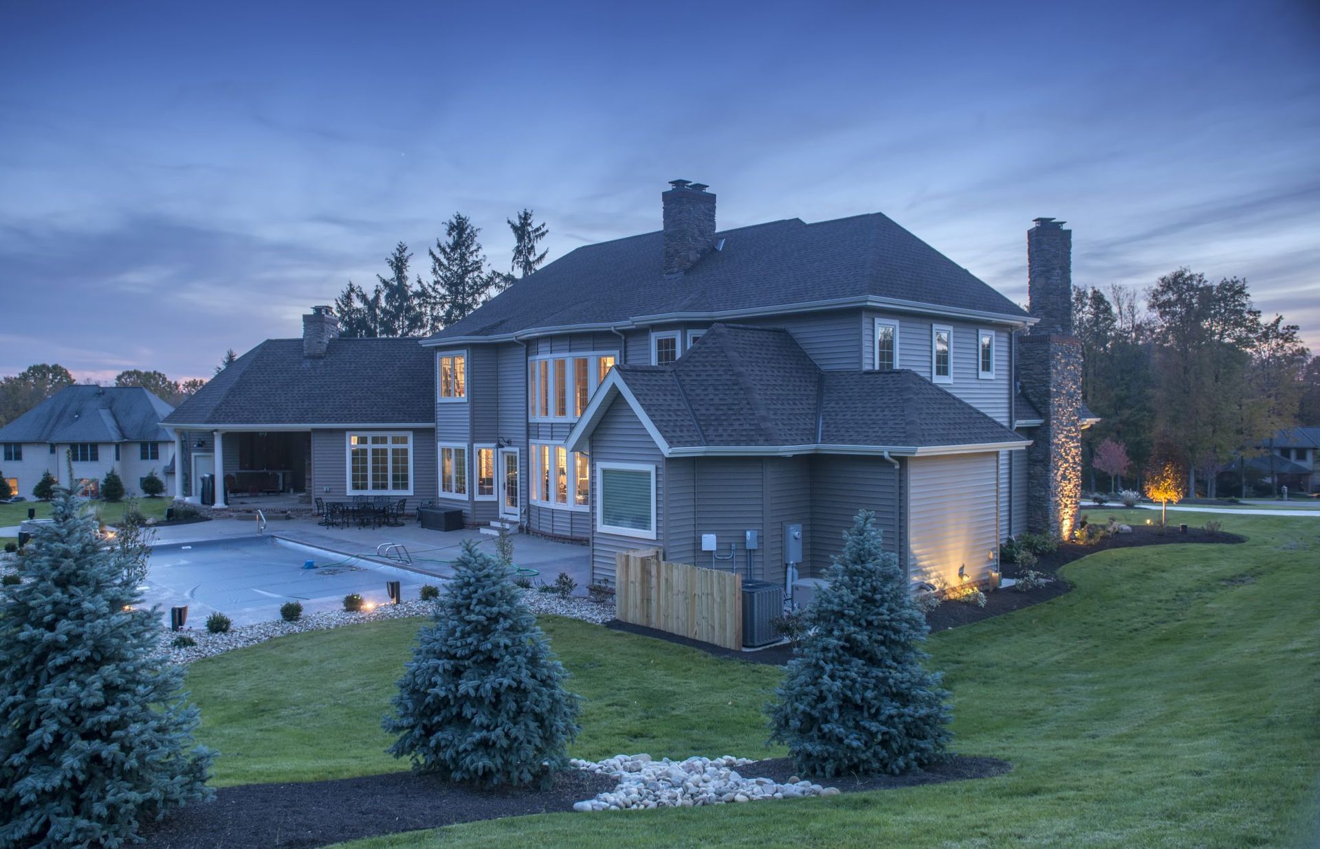 A large house with a pool in the backyard is lit up at night.