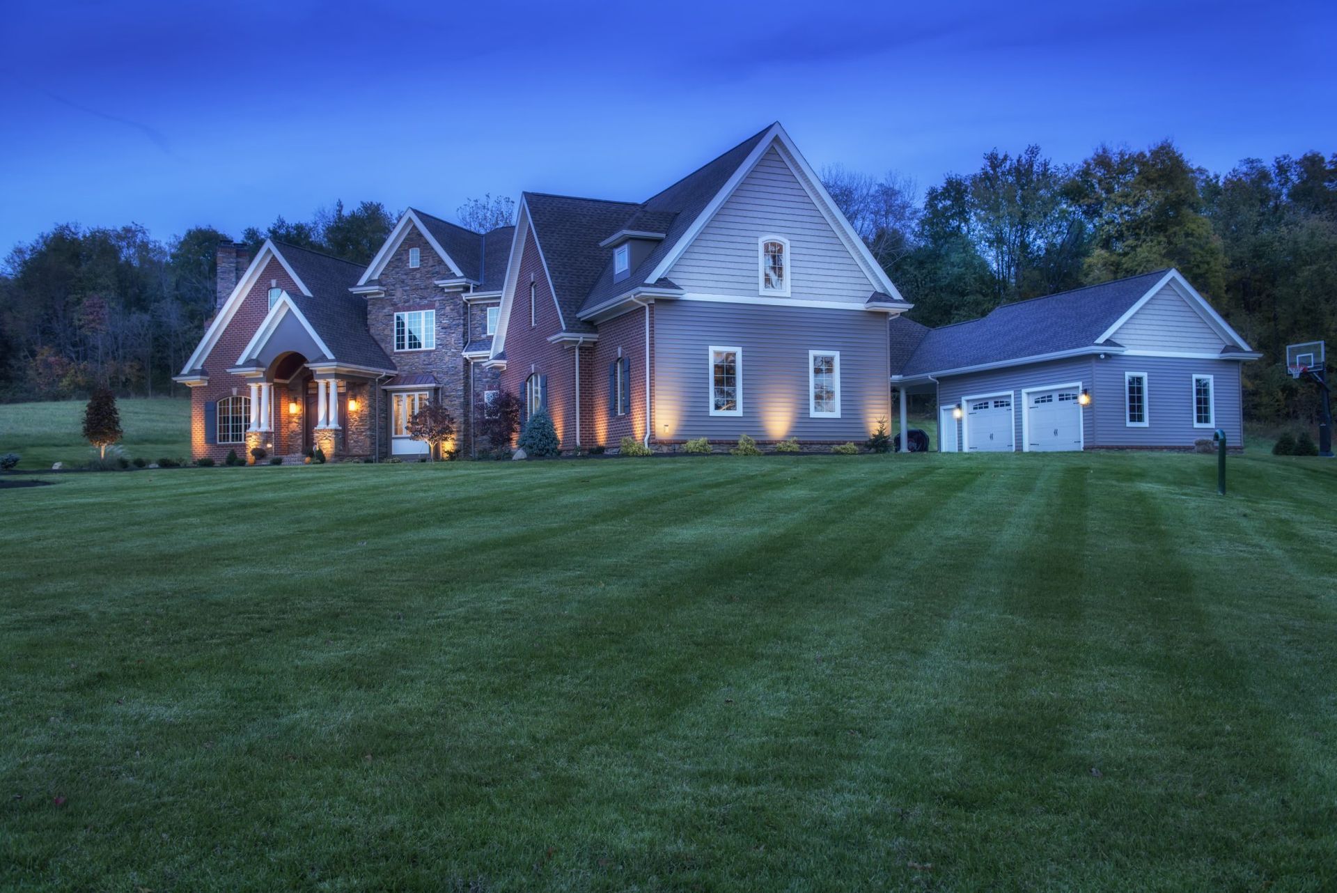 A large house is sitting on top of a lush green field.