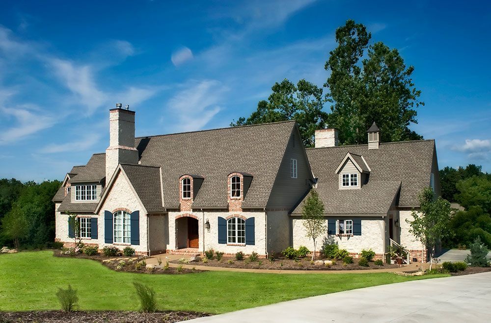 A large white house with a gray roof and blue shutters.