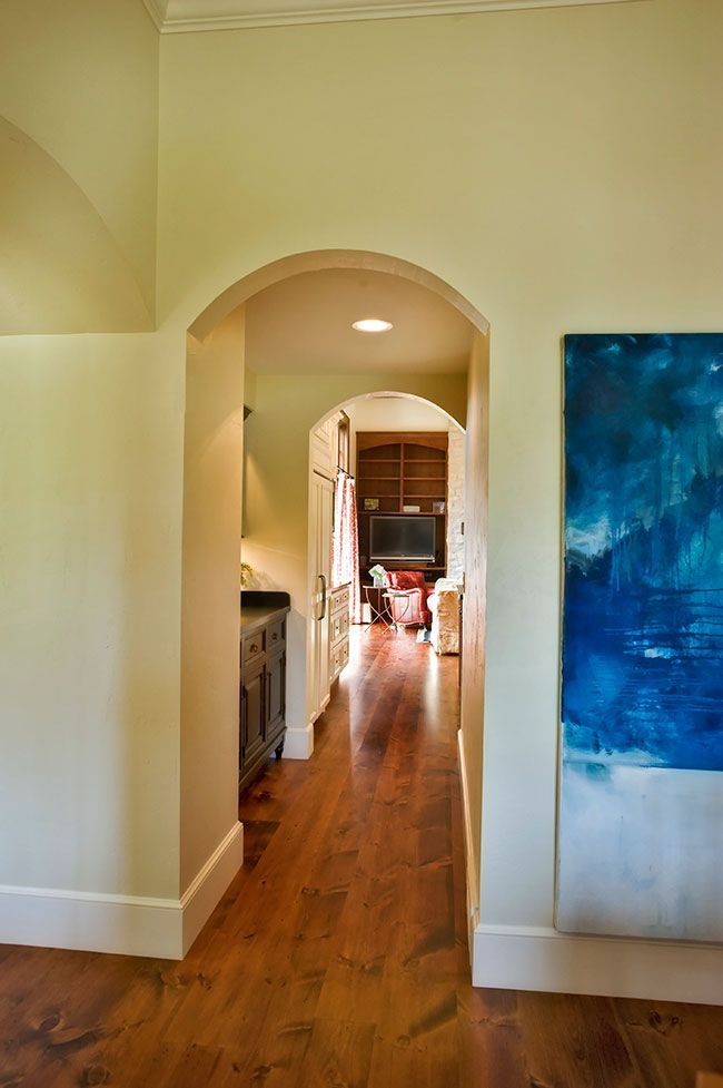 A hallway with a blue painting on the wall leading to a living room.