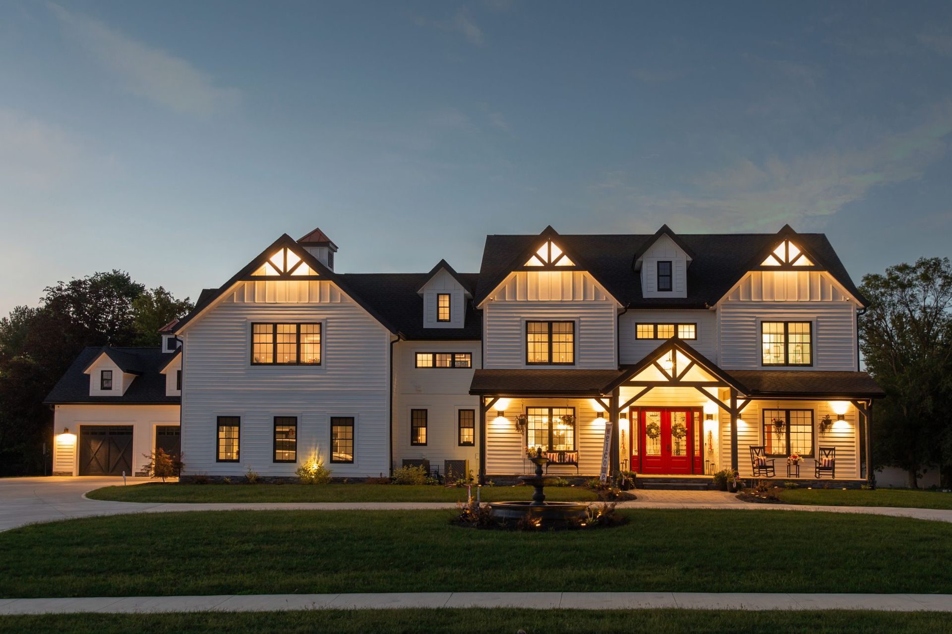 A large white house with a red door is lit up at night