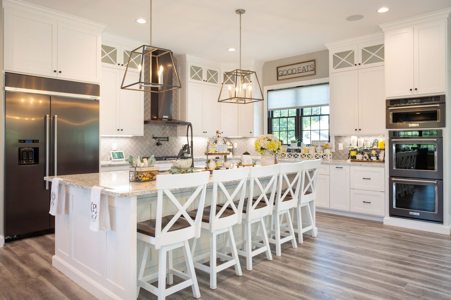 A kitchen with white cabinets , stainless steel appliances , and a large island.