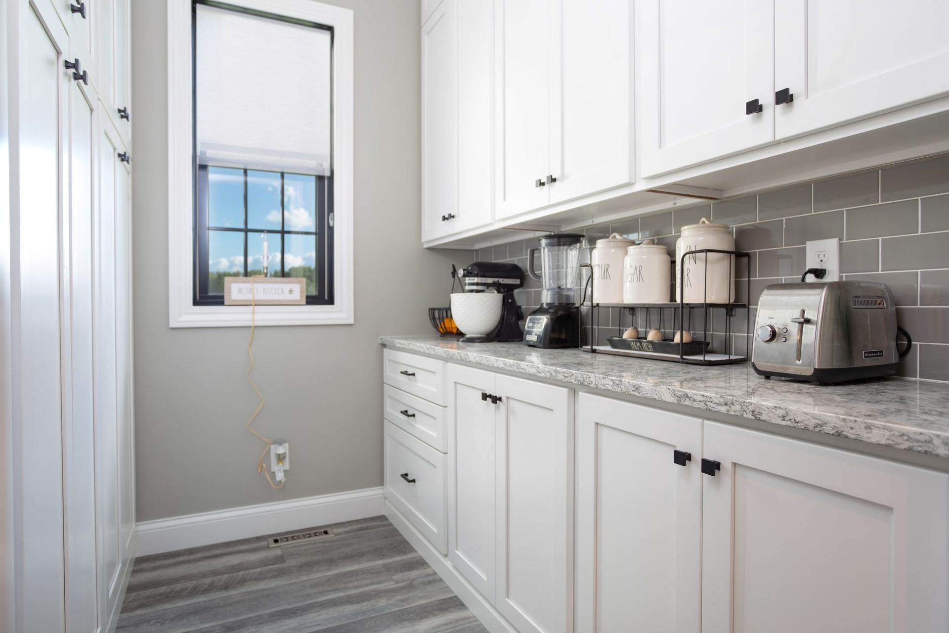 A kitchen with white cabinets , granite counter tops , and a window.