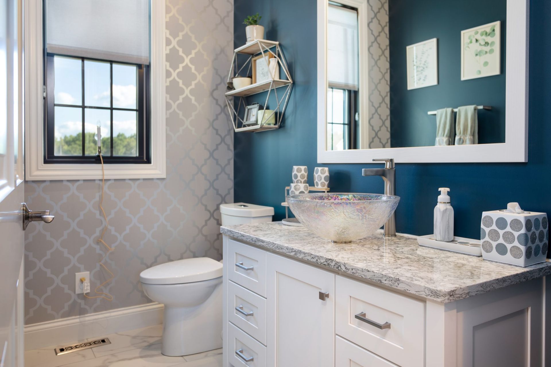 A bathroom with a toilet , sink , mirror and window.