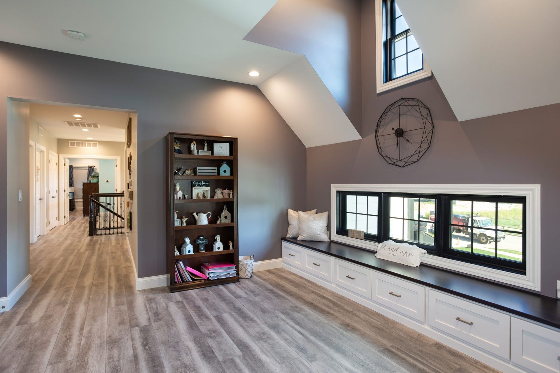 A living room with a window seat and a clock on the wall.