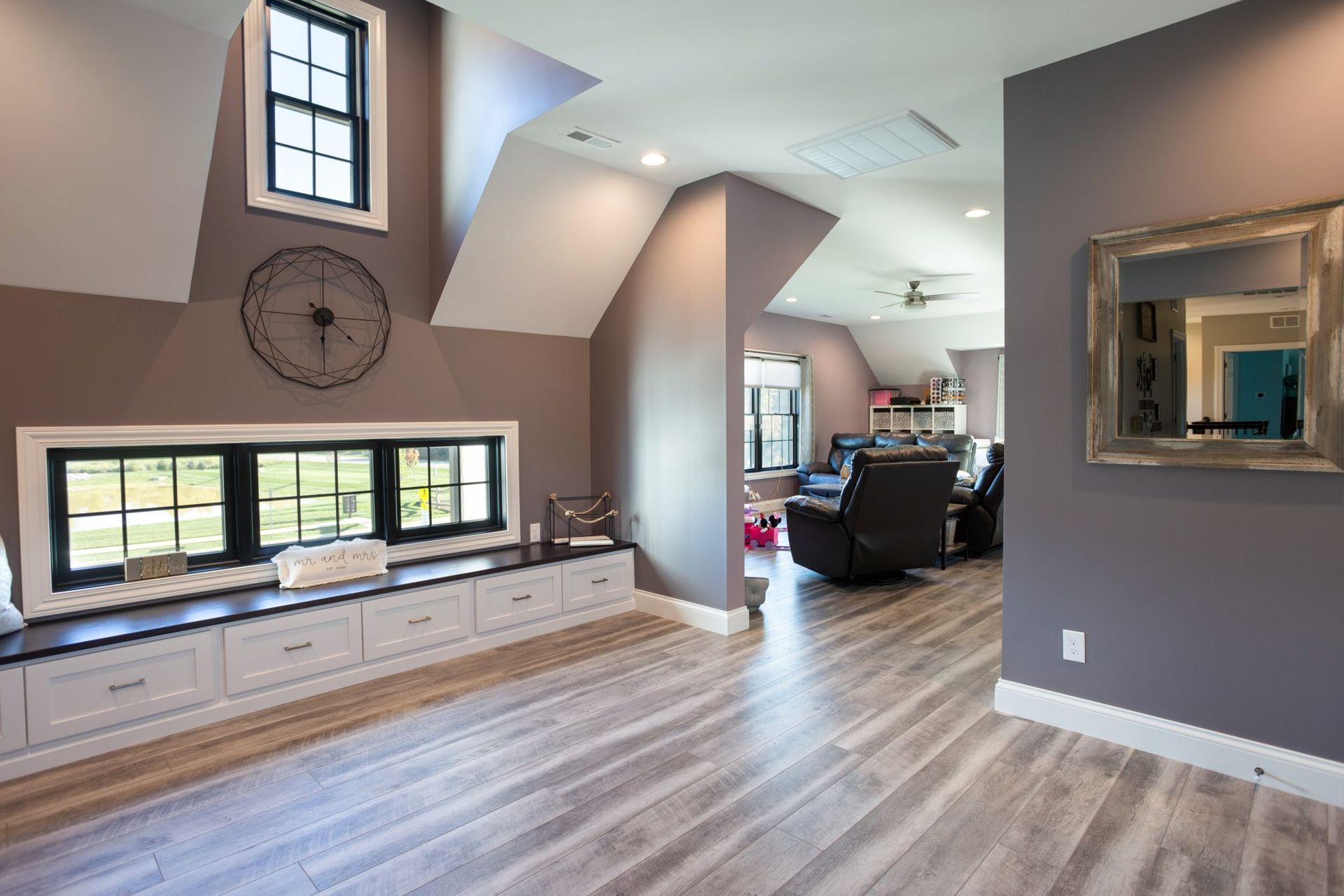 A living room with a clock on the wall and a mirror.
