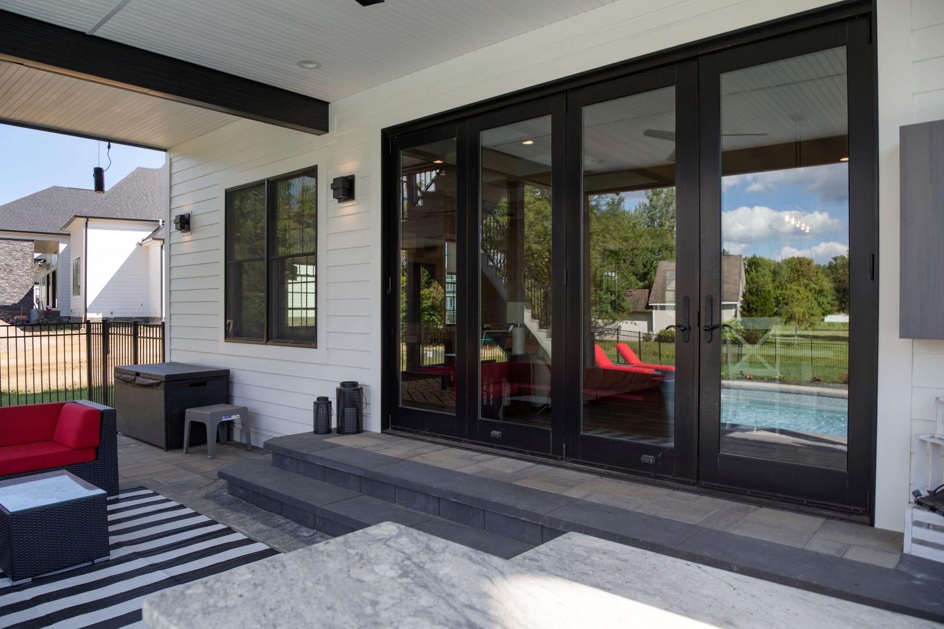 A patio with a black and white rug and sliding glass doors leading to a pool.