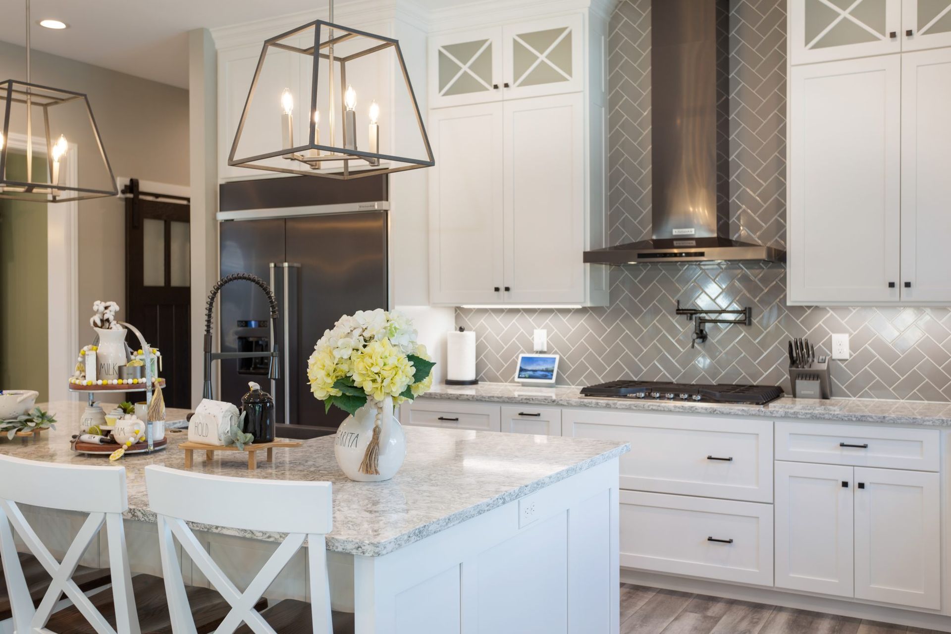 A kitchen with white cabinets , granite counter tops , stainless steel appliances and a large island.
