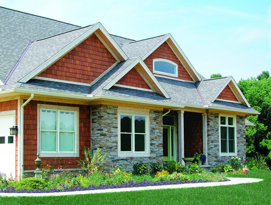 A large brick and stone house with a gray roof.