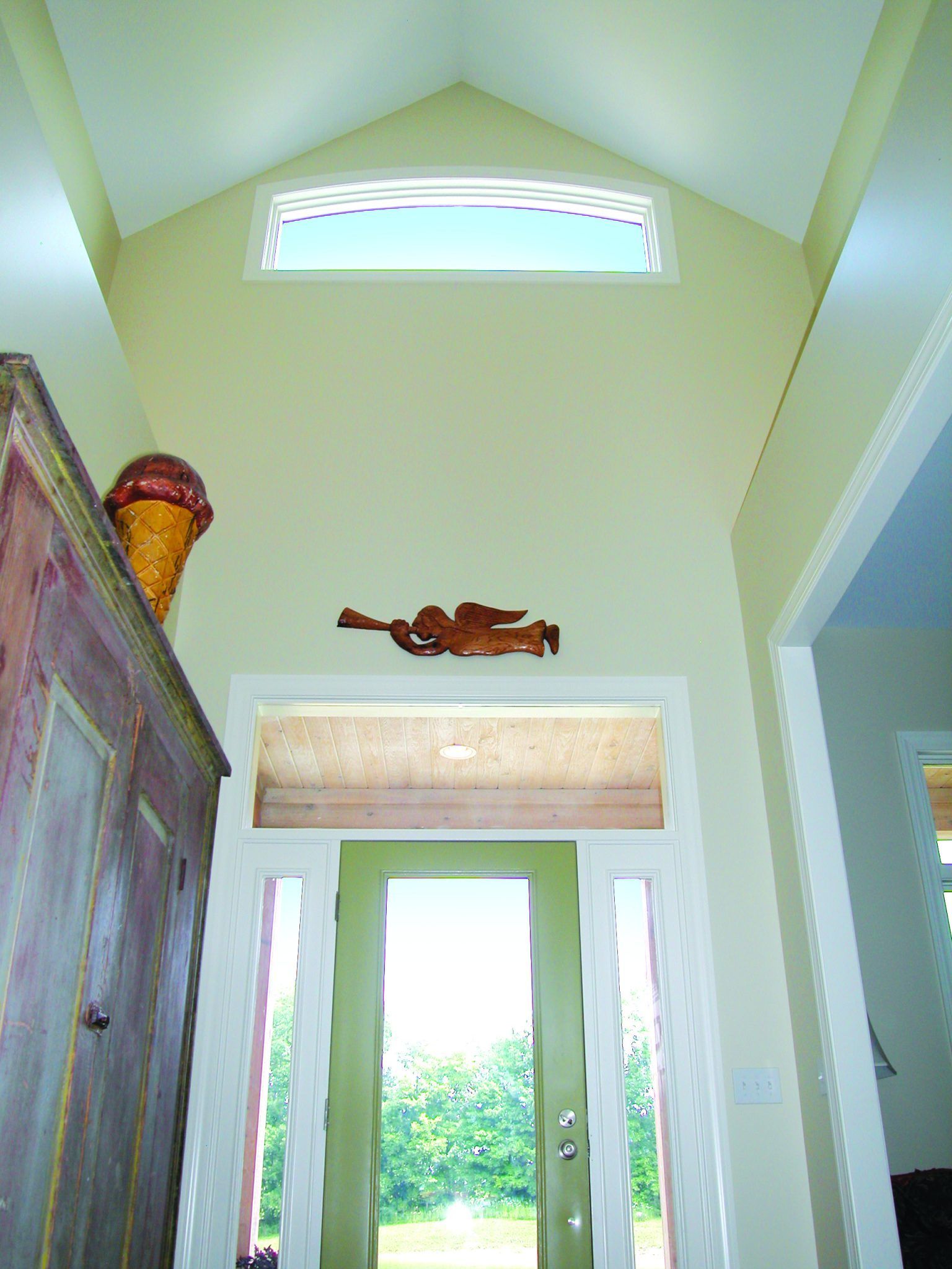 A hallway with a vaulted ceiling and a green door.