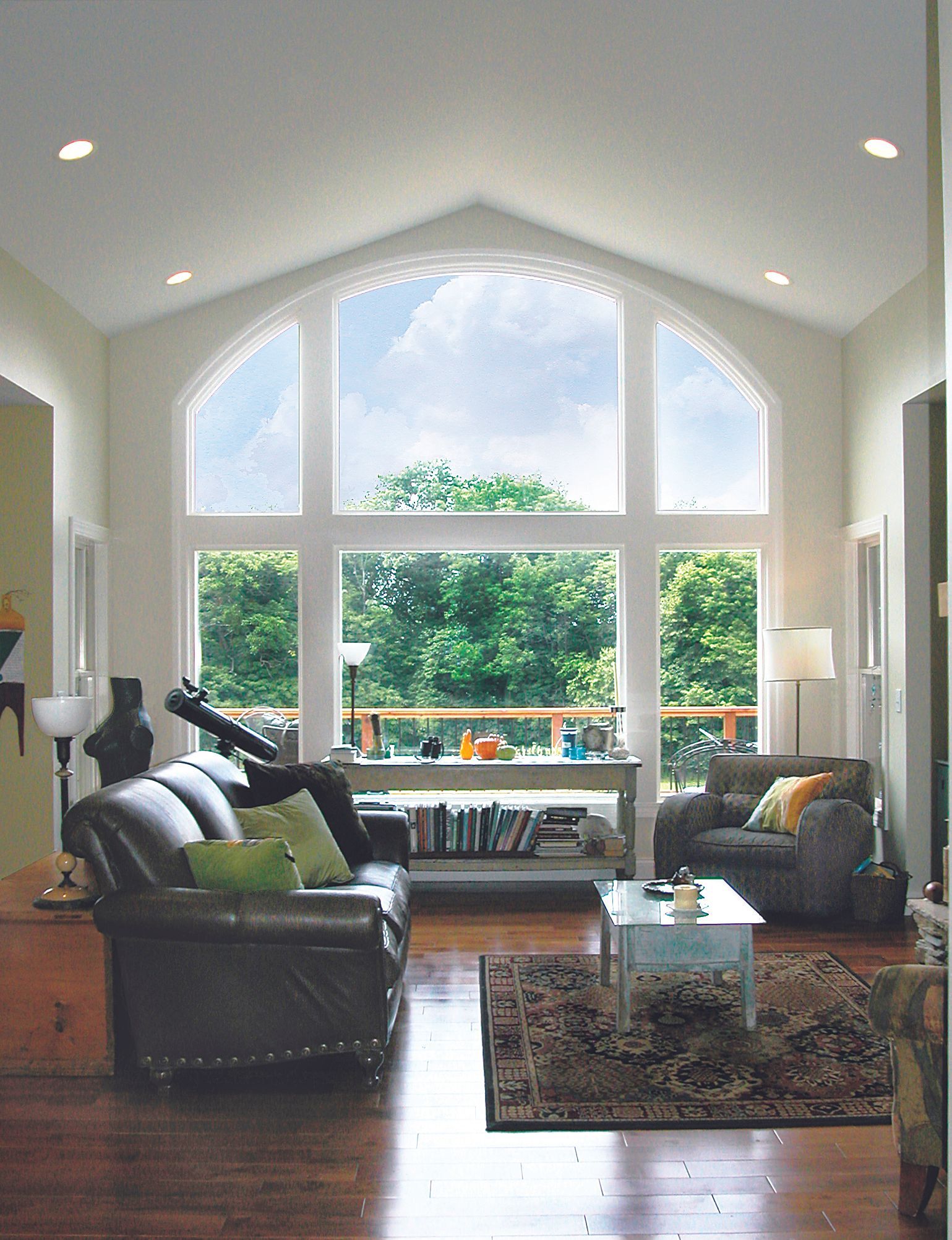 A living room with a vaulted ceiling and large open windows.