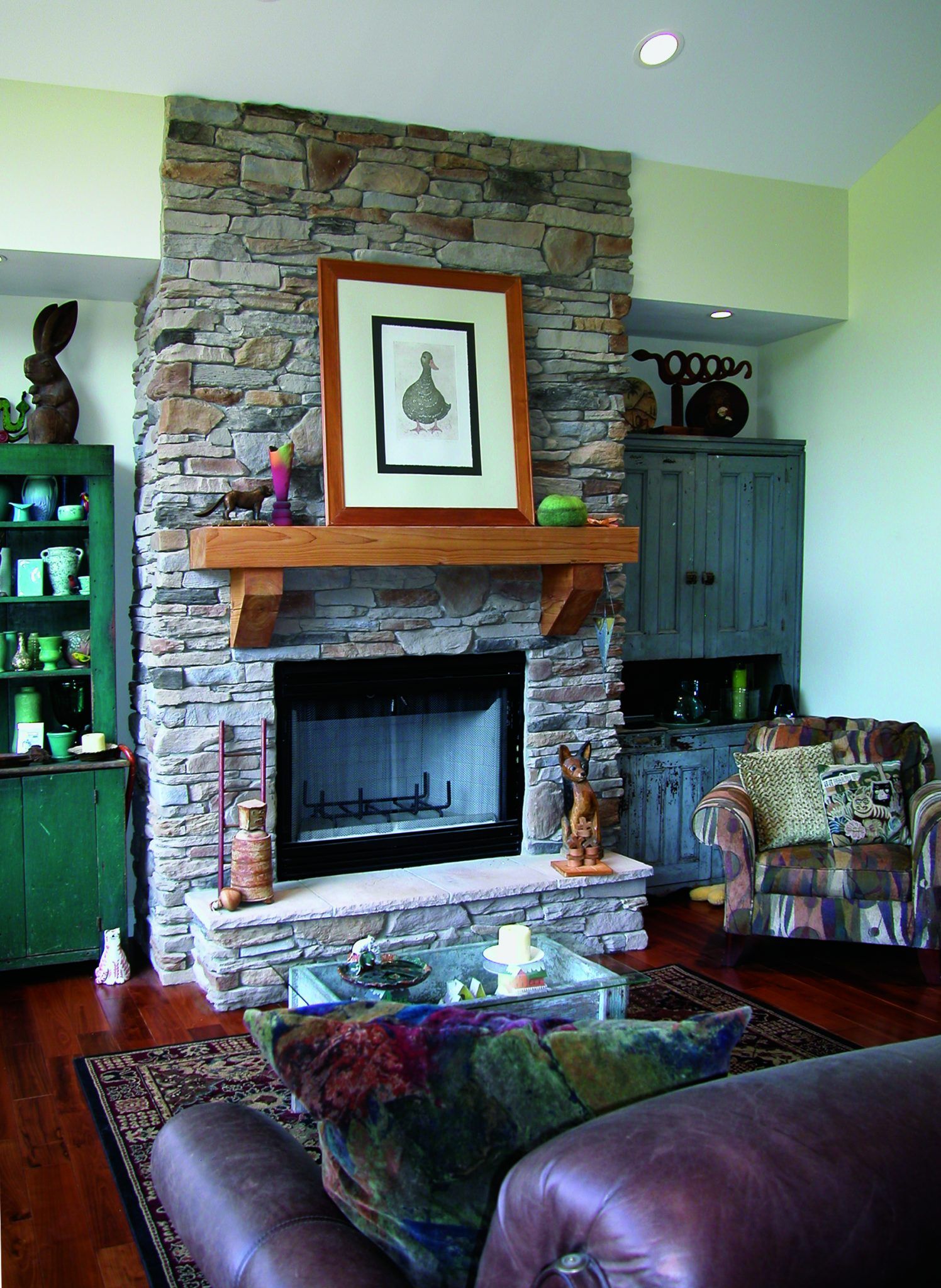 A living room with a fireplace, a picture above it on the mantle, and cabinets.